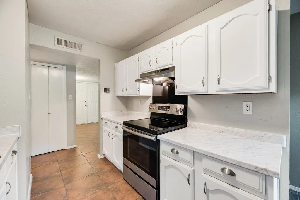 Kitchen featuring white cabinetry, stainless steel range, white countertops, and terracotta-toned tile flooring