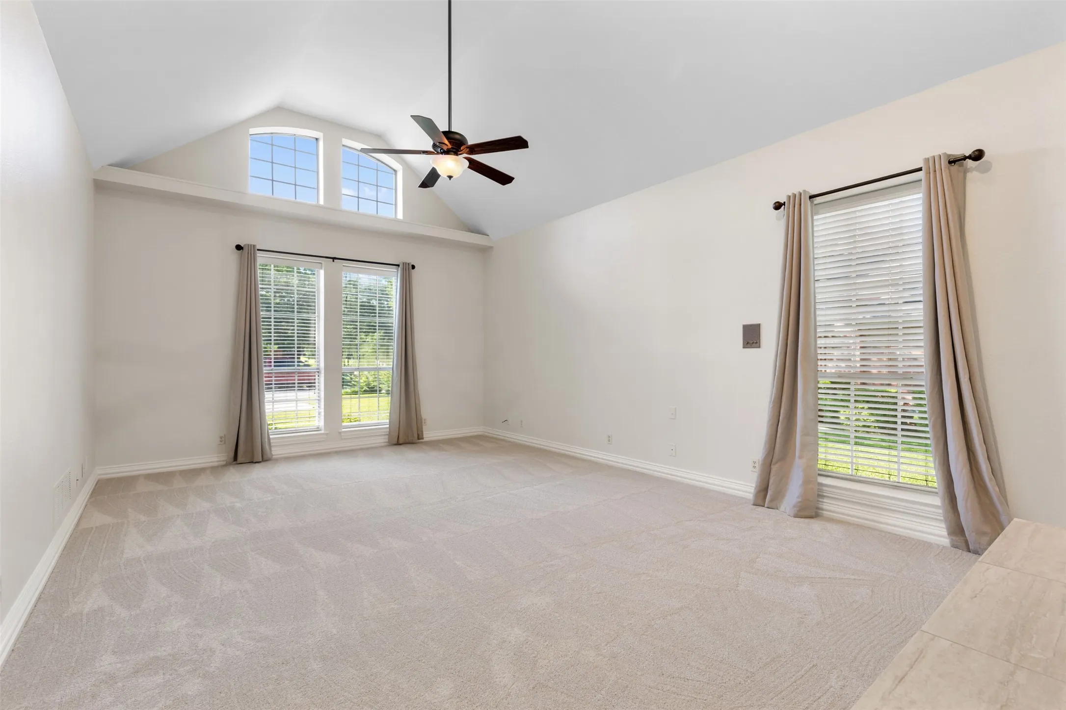 Spacious primary bedroom with light pouring in and vaulted ceilings.