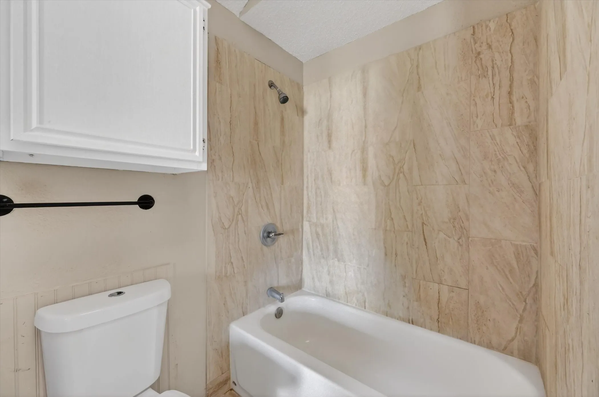 Bathtub and shower combination featuring neutral-toned wall tiles