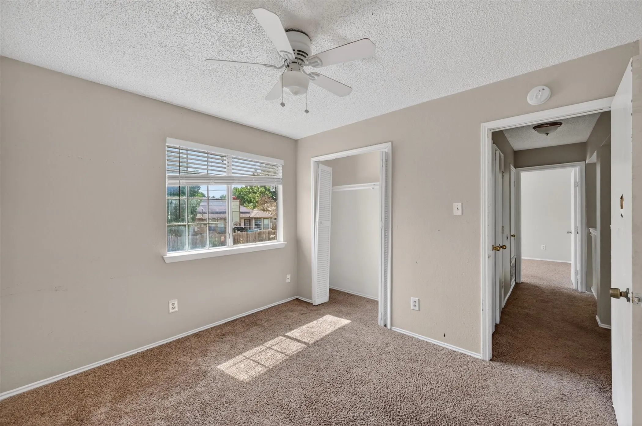 Carpeted room with neutral painted walls and a textured ceiling
