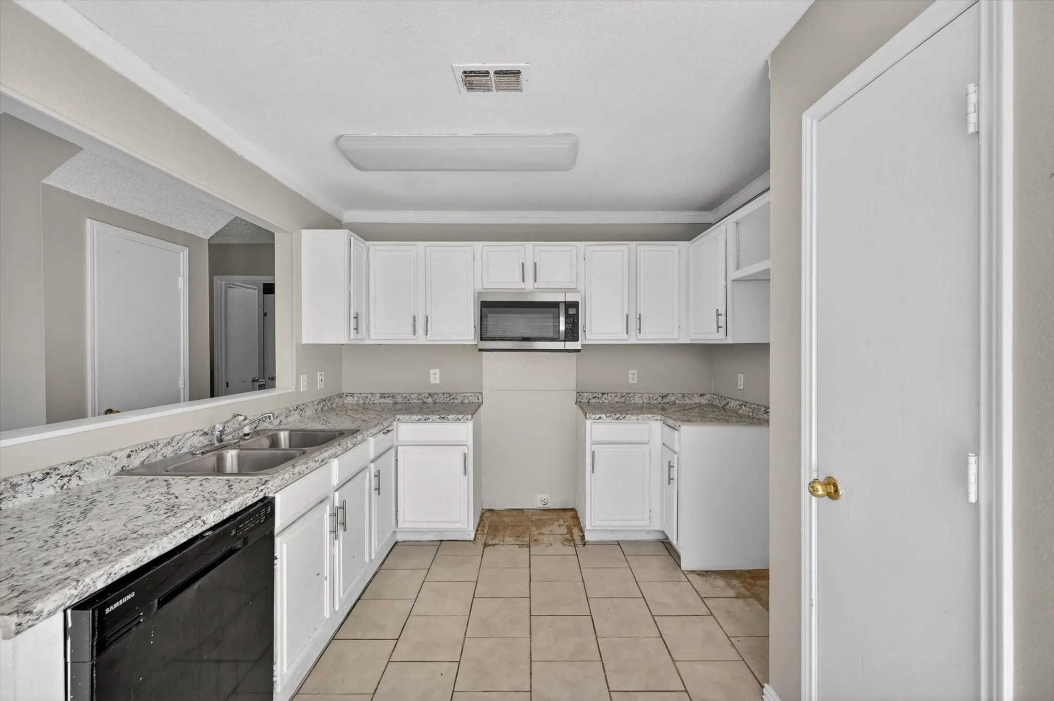 Kitchen featuring white cabinetry, light-toned countertops, a double basin sink, and a built-in microwave