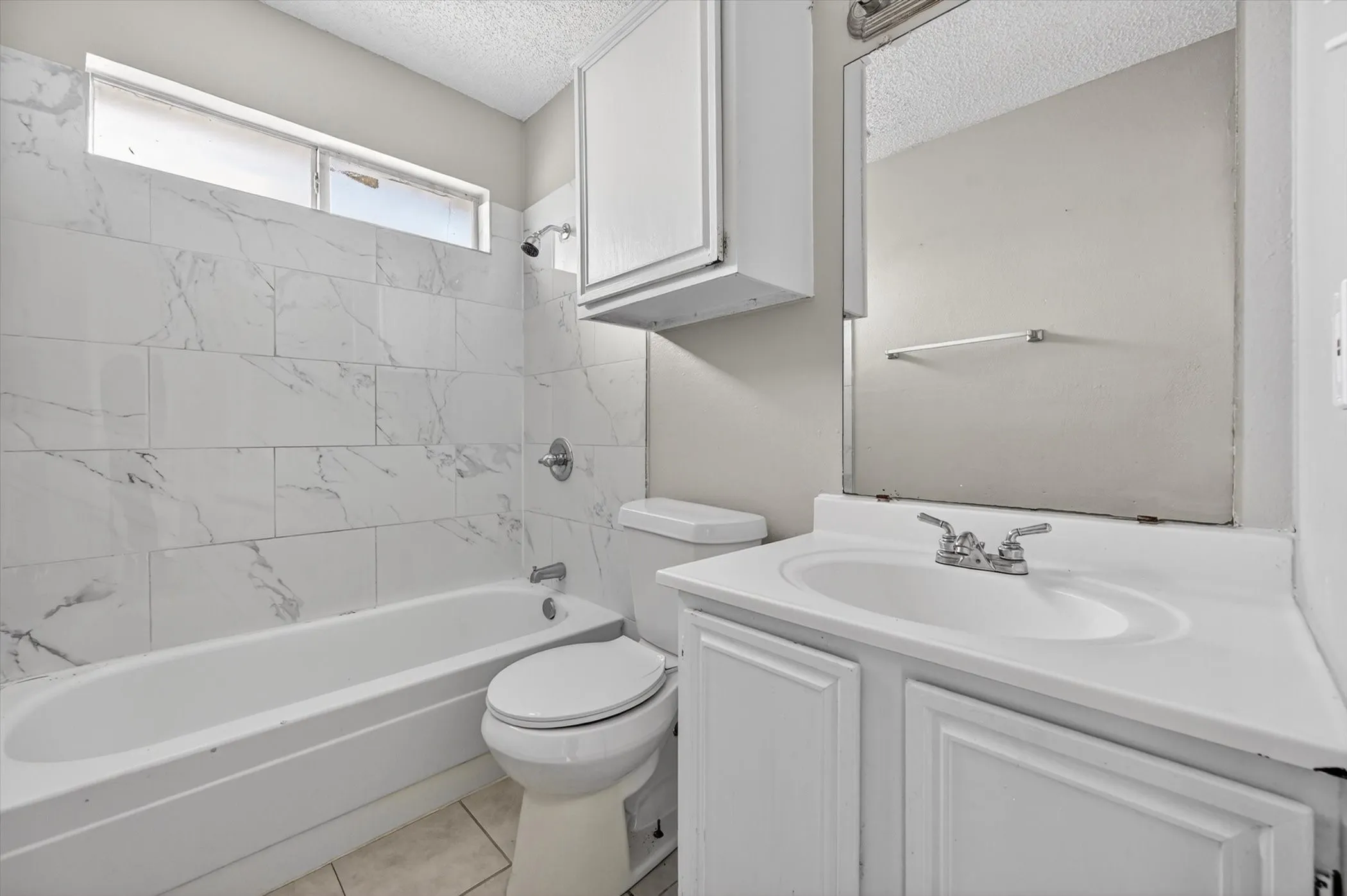 Bathroom featuring a white vanity with integrated sink, white cabinetry, and a mirrored wall
