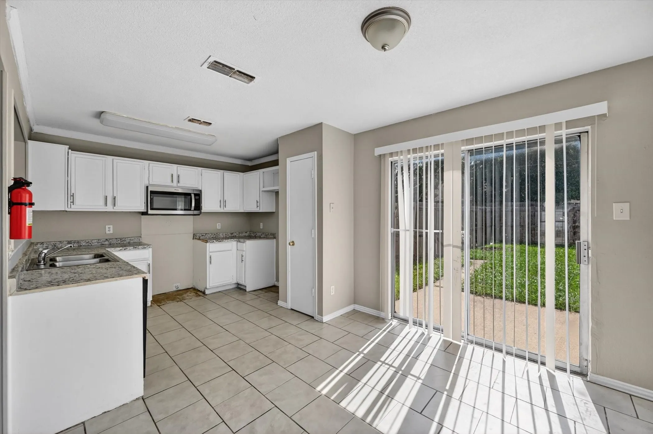 Kitchen area featuring white cabinetry, light-toned countertops, and an integrated microwave