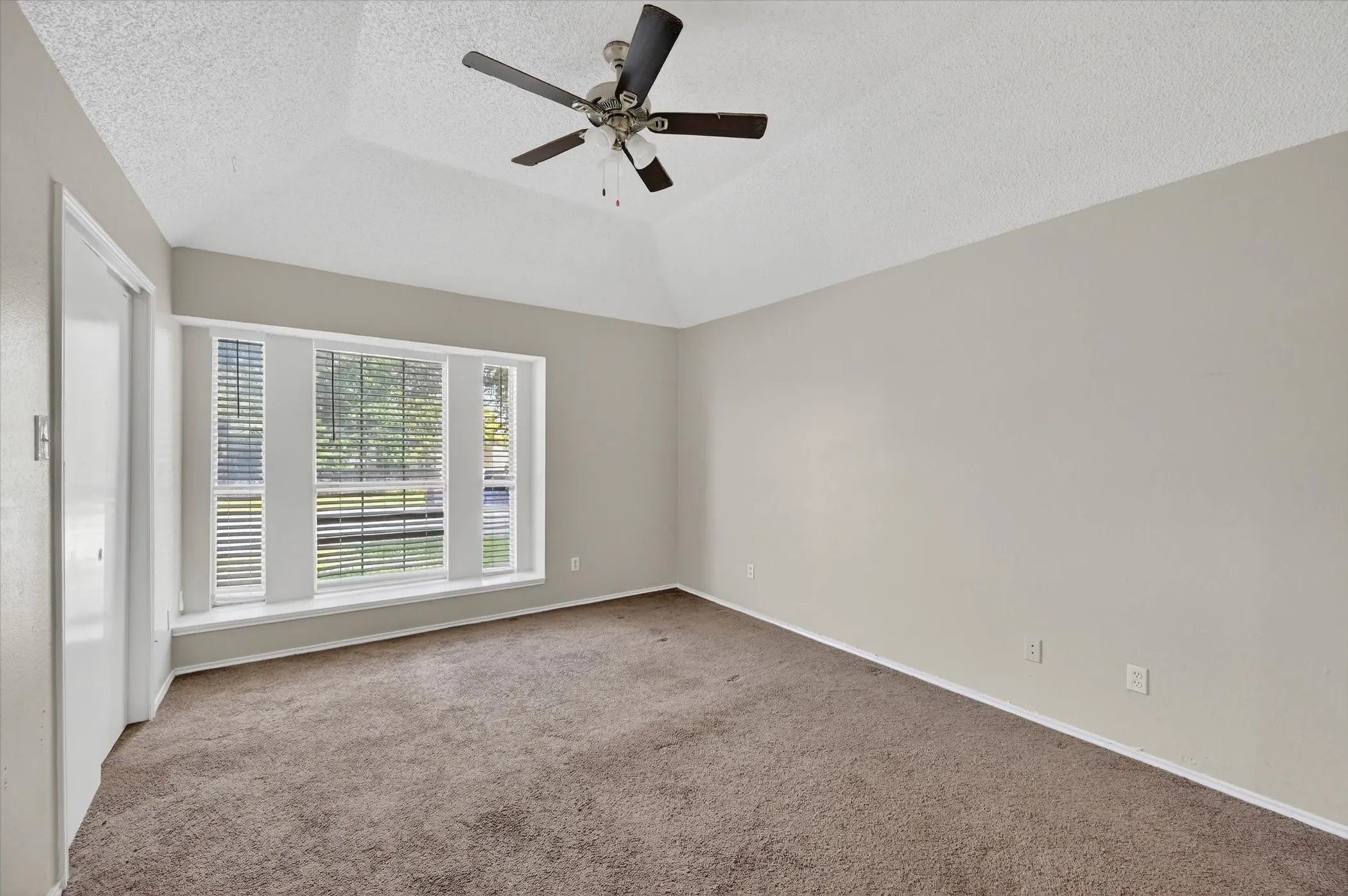 Carpeted interior space featuring a vaulted ceiling and a ceiling fan
