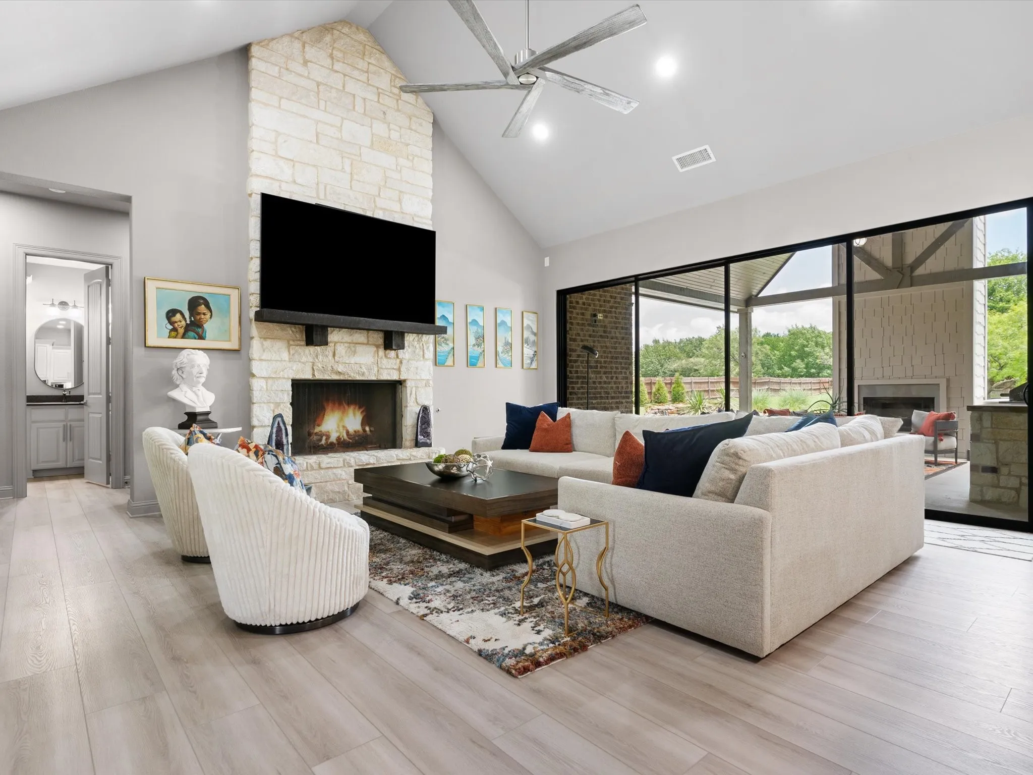 Large living room featuring luxury vinyl plank flooring, abundant natural light, and a dramatic oversized sliding glass door.
