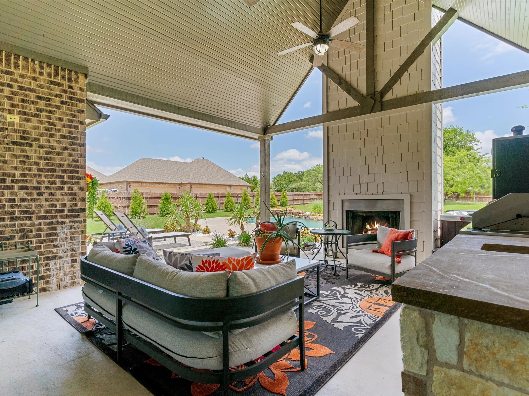 Covered outdoor living area overlooking the pool and backyard oasis