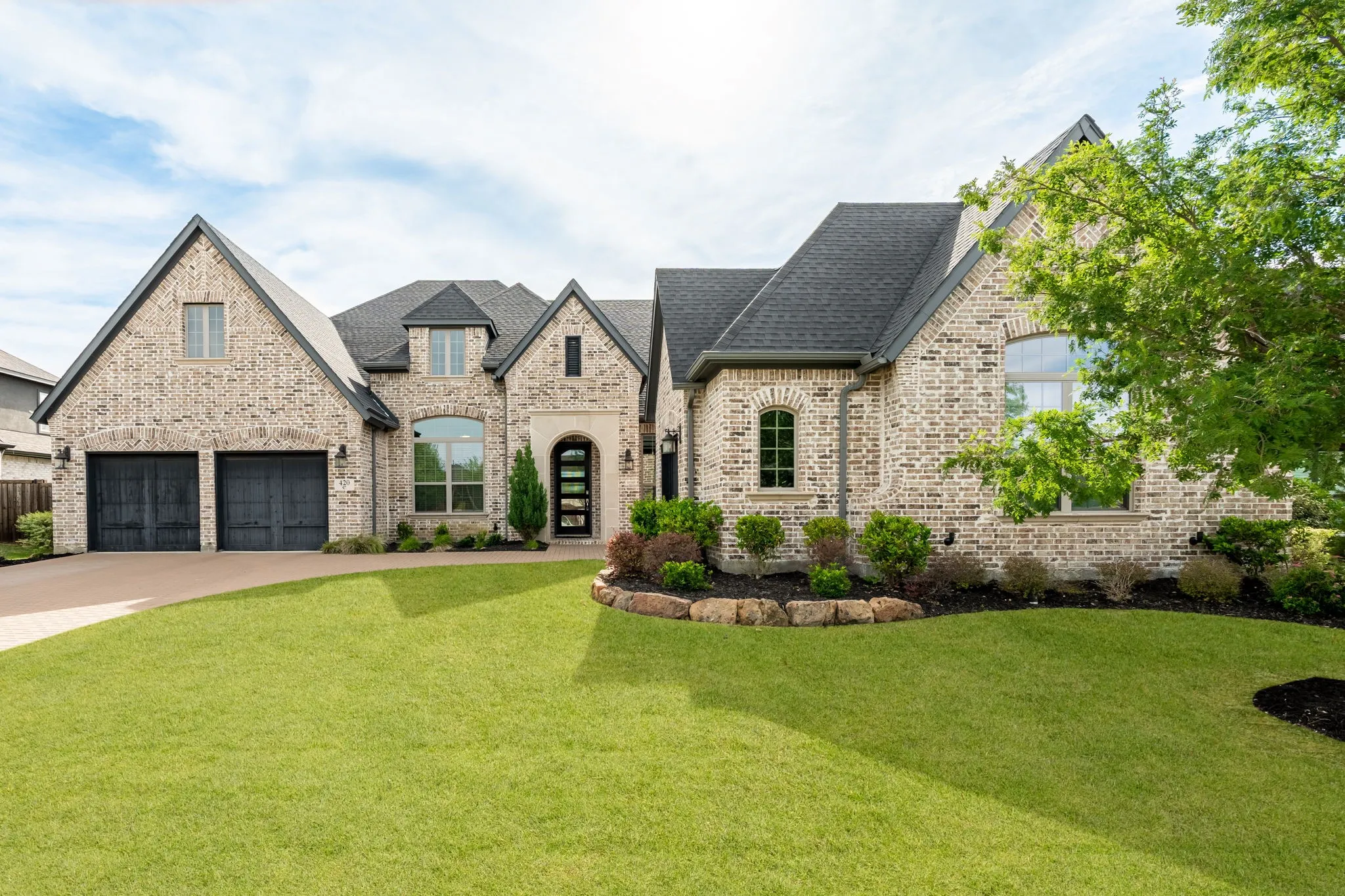 Brick exterior with a dark shingle roof and a two-car garage