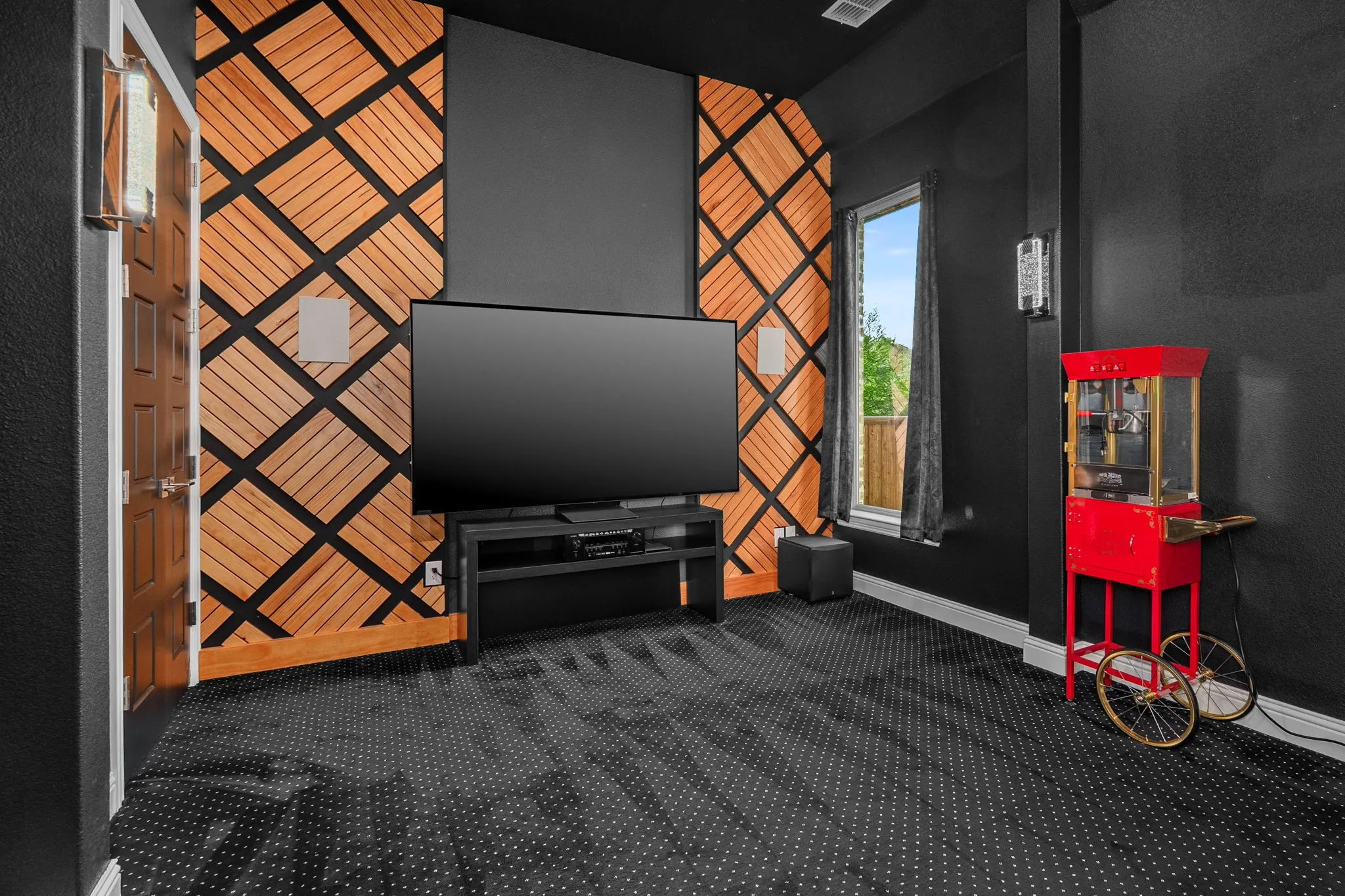 Custom designed wood accented wall in media room featuring tiered seating, dark walls, and ceiling-mounted recessed lighting