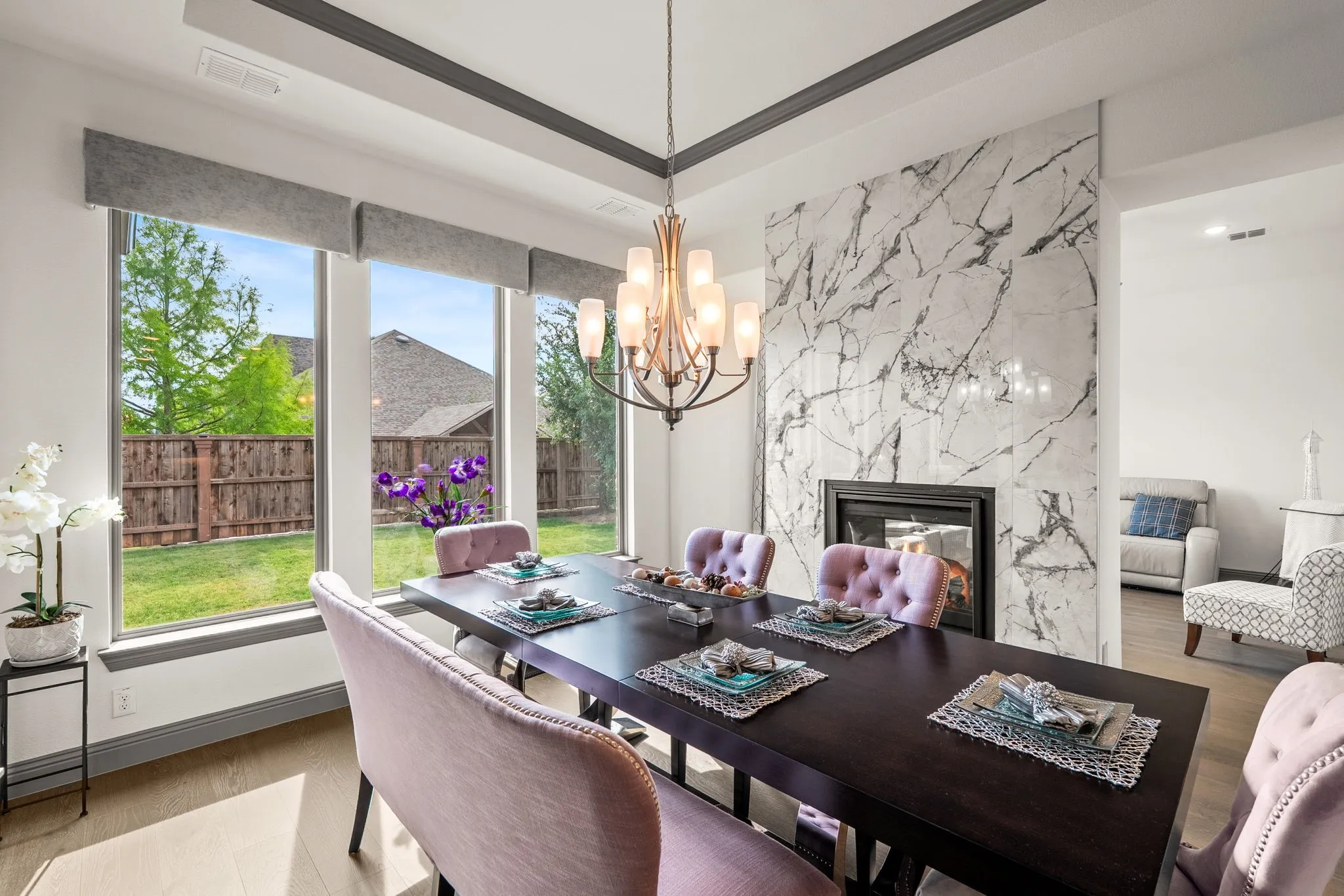 Dining area featuring a marble-clad fireplace, a contemporary chandelier, and wood-finish flooring