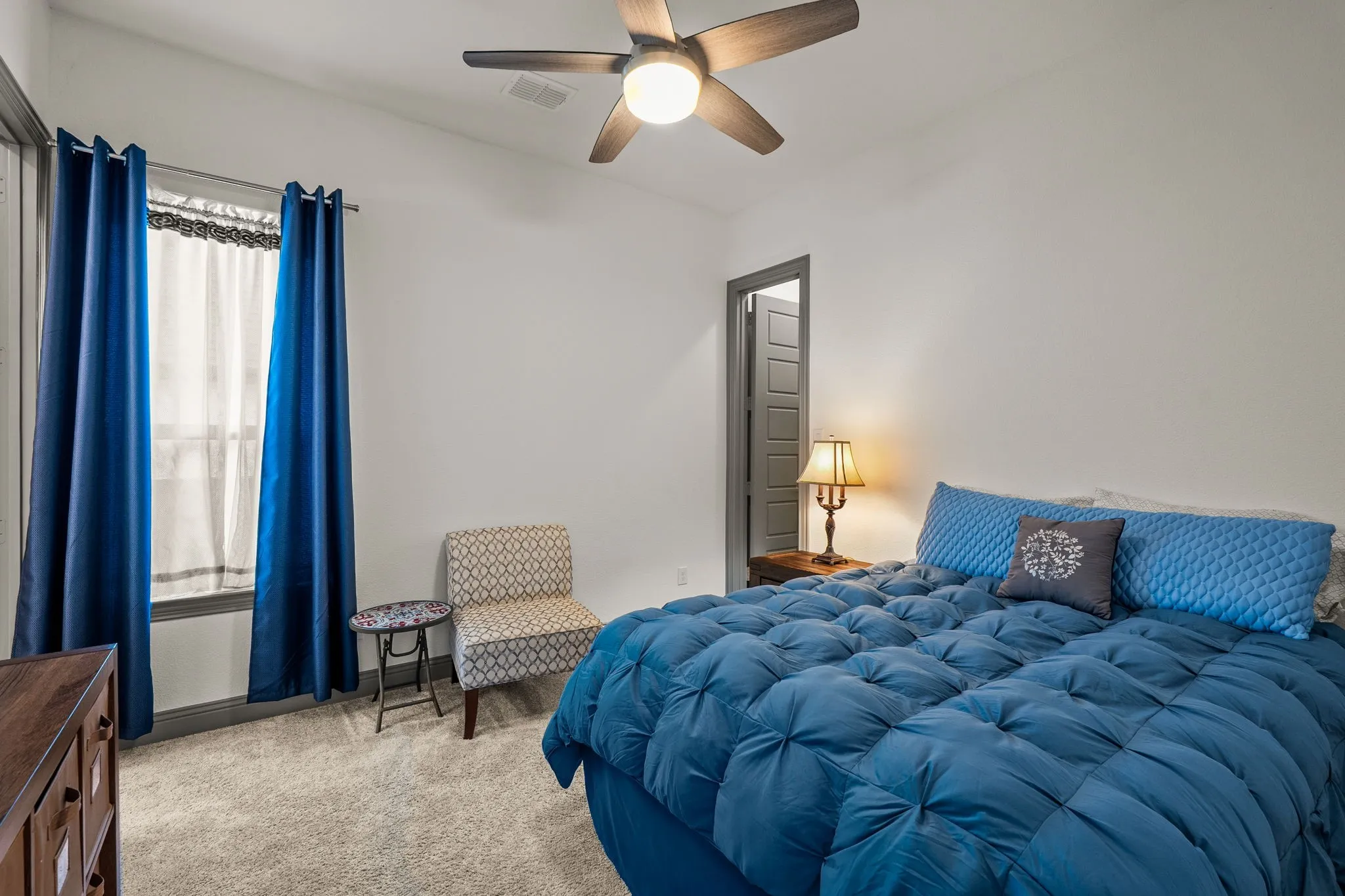 Spacious bedroom featuring light-colored carpeting and a window with dark trim