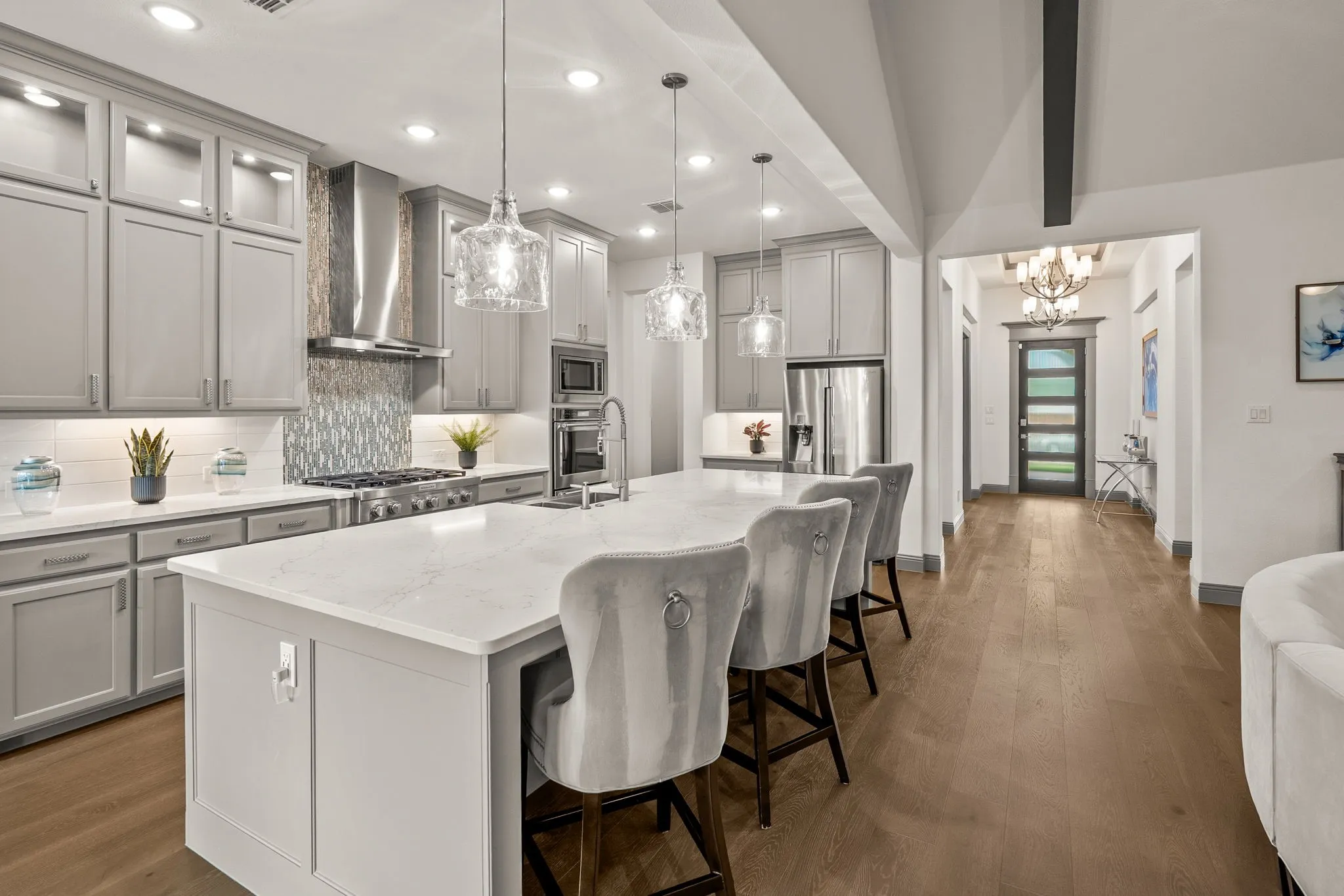 Contemporary kitchen featuring light gray cabinetry, a central island with a light-colored countertop, stainless steel appliances, and wood-finish flooring