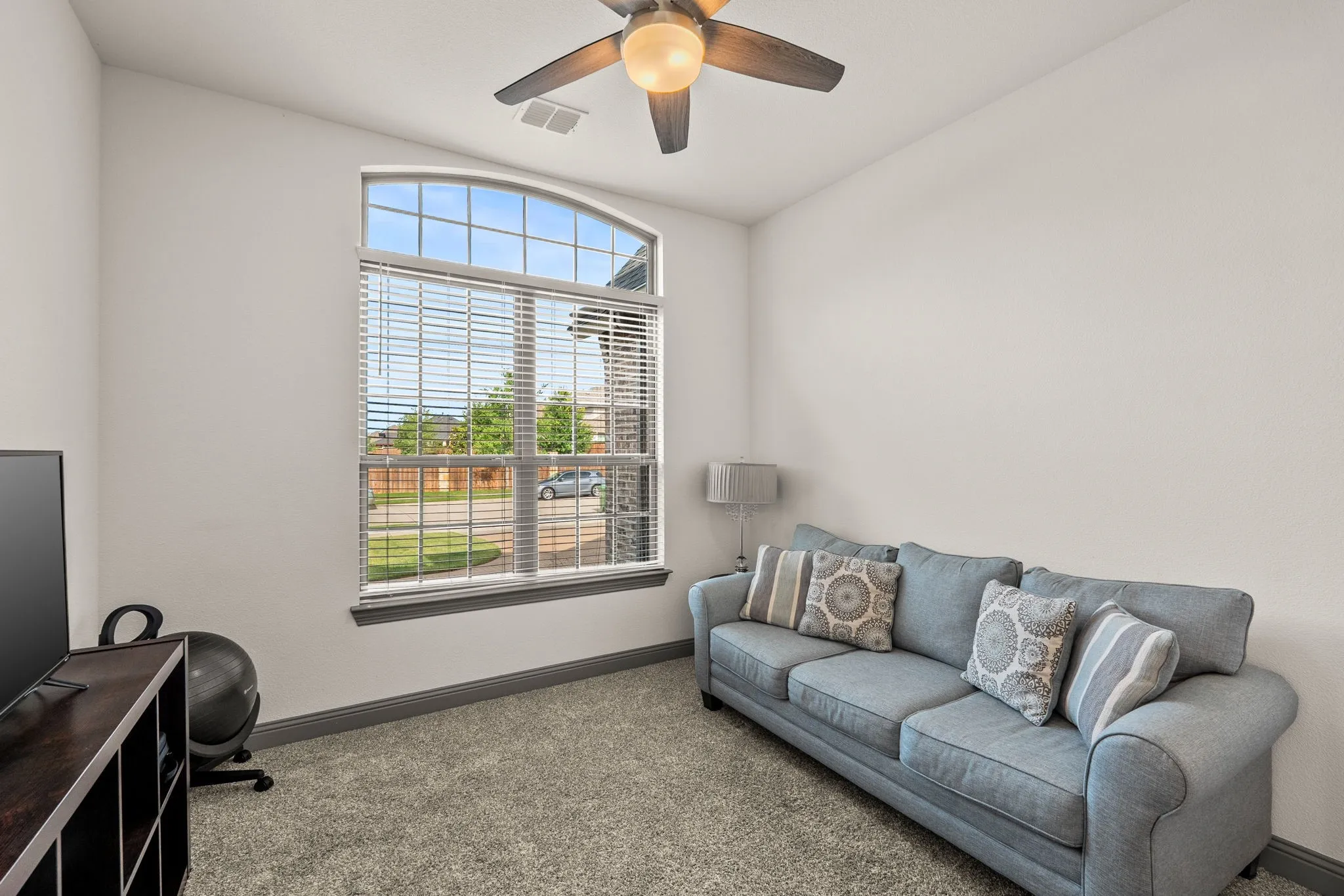 Spacious front bedroom featuring front window view, ceiling-lighting and fan