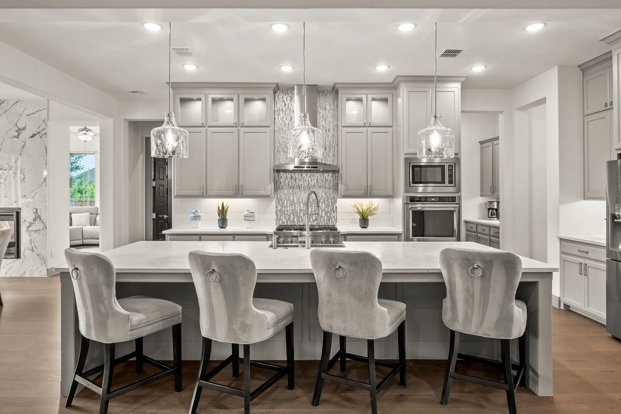 Kitchen featuring a large central island with seating for four, light gray cabinetry, stainless steel appliances, and wood-finish flooring