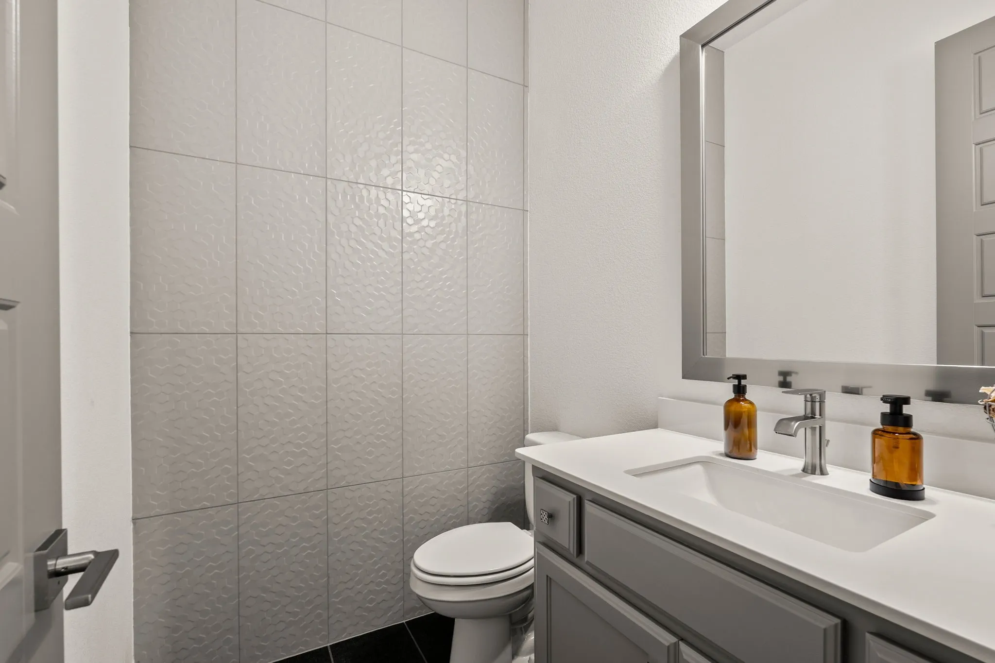 Bathroom featuring a grey vanity with a white countertop, an undermount sink, a sleek silver faucet, and a large framed mirror
