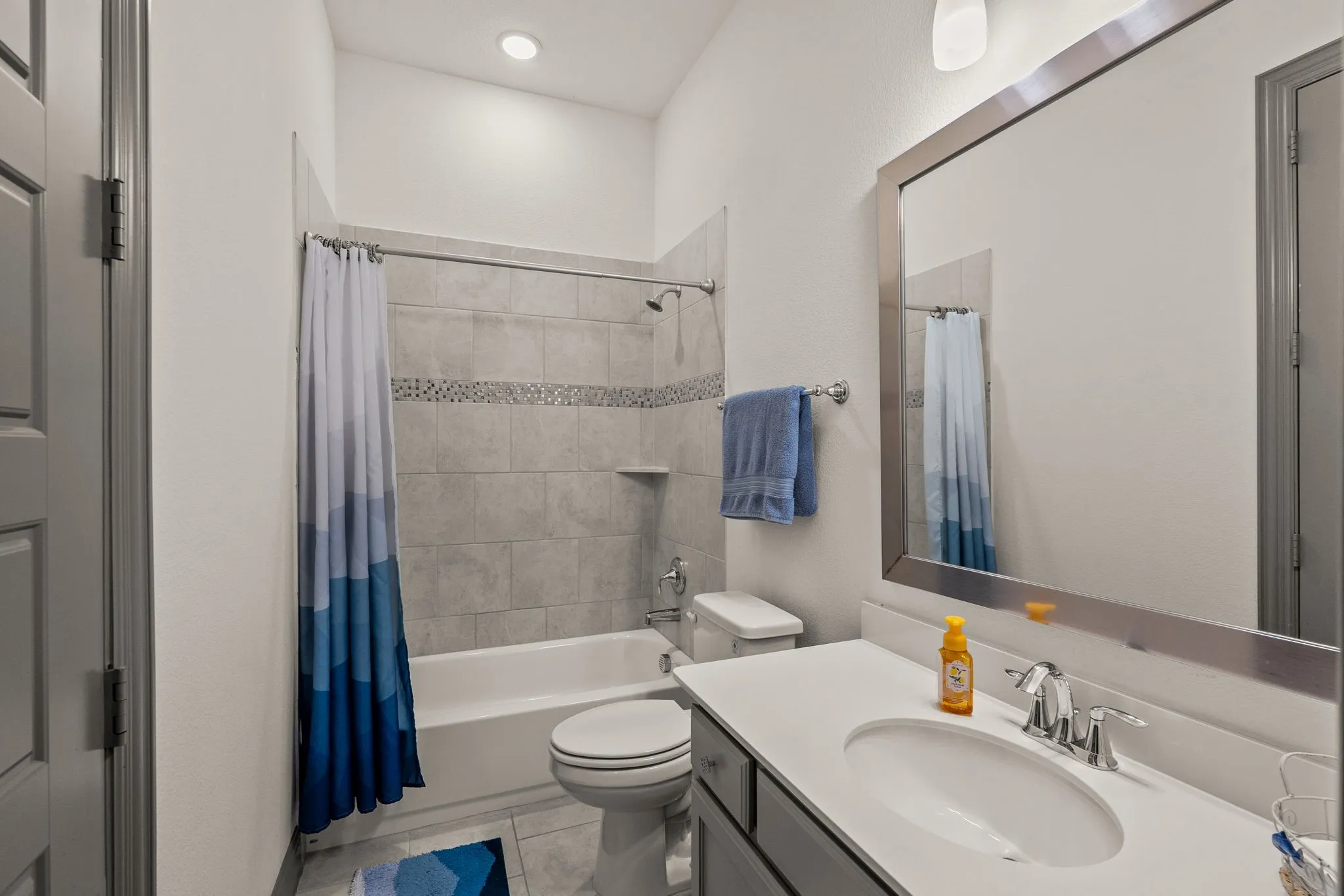 Bathroom featuring a vanity with an oval undermount sink, a chrome faucet, and a large framed mirror