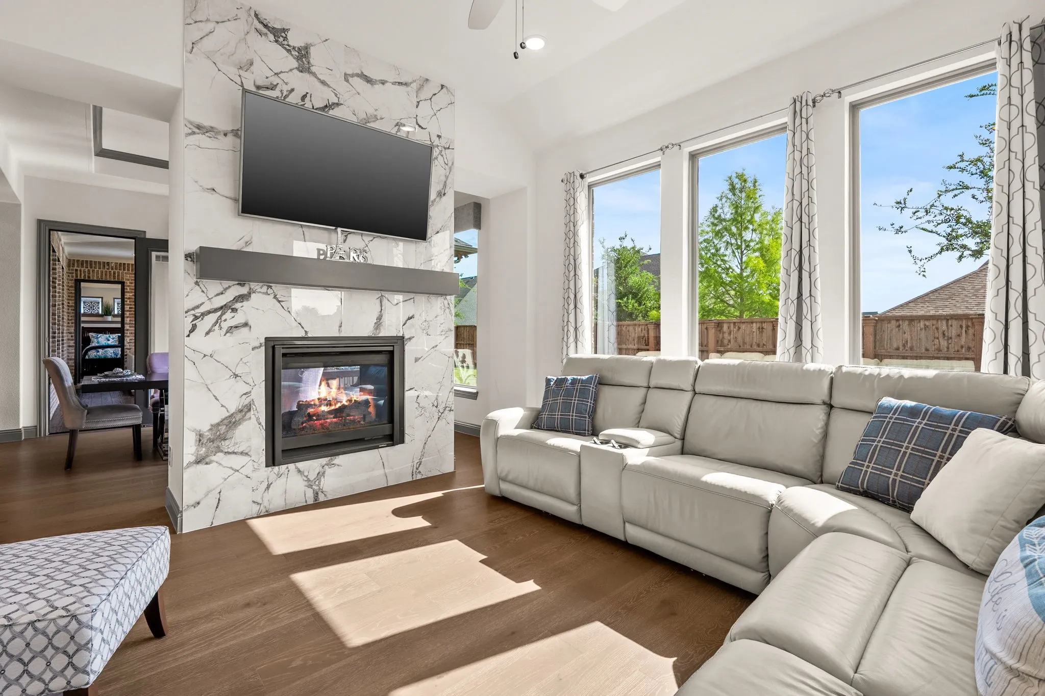 Living area featuring a floor-to-ceiling accent wall with a built-in fireplace, wood-finish flooring, and multiple large windows