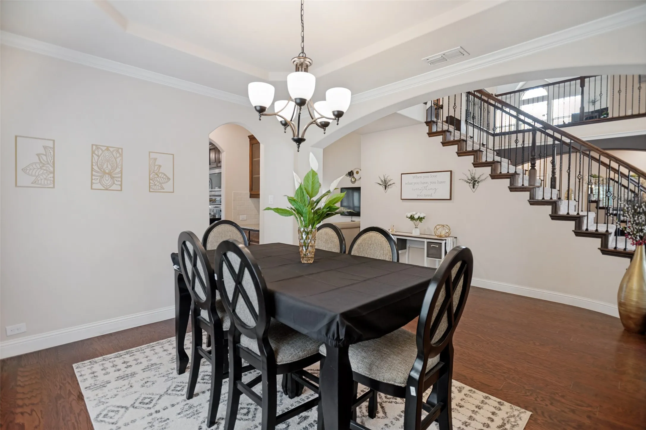 Formal dining area featuring rich wood-finish flooring, a tray ceiling, and a traditional chandelier