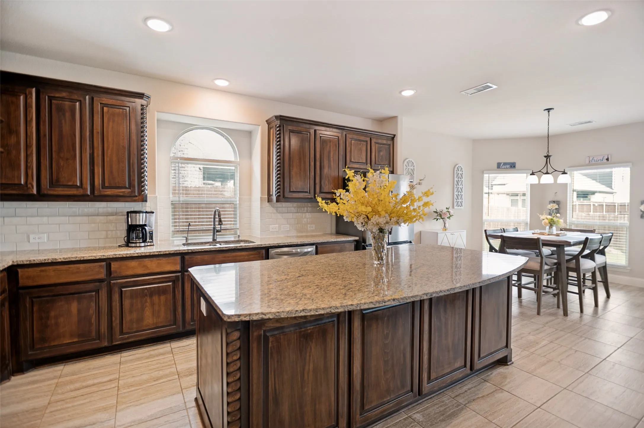 Spacious kitchen featuring a large island with a stone countertop, dark wood cabinetry, subway tile backsplash, and recessed lighting