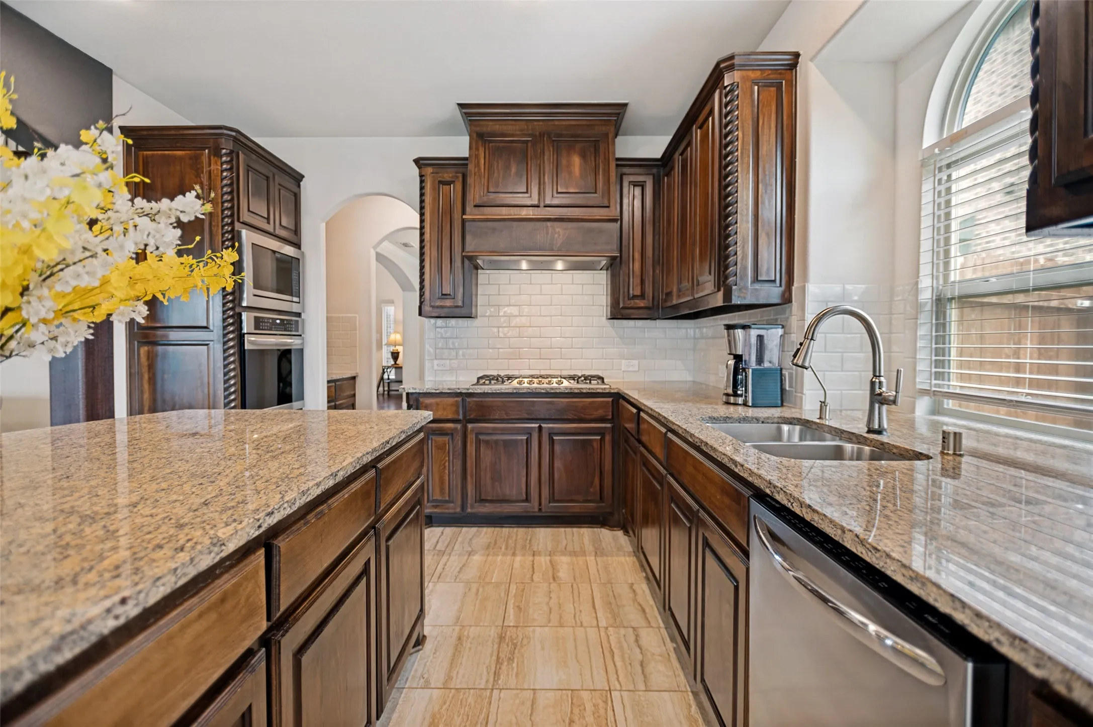 Kitchen featuring a built-in oven, gas cooktop, stainless steel appliances, granite countertops, and tile flooring