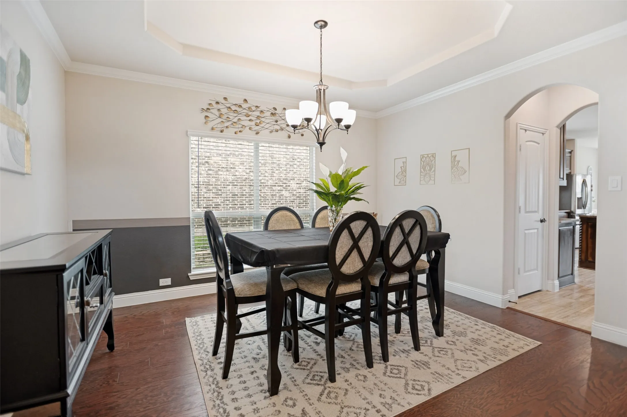 Formal dining area featuring wood-finish flooring, a tray ceiling, and a chandelier