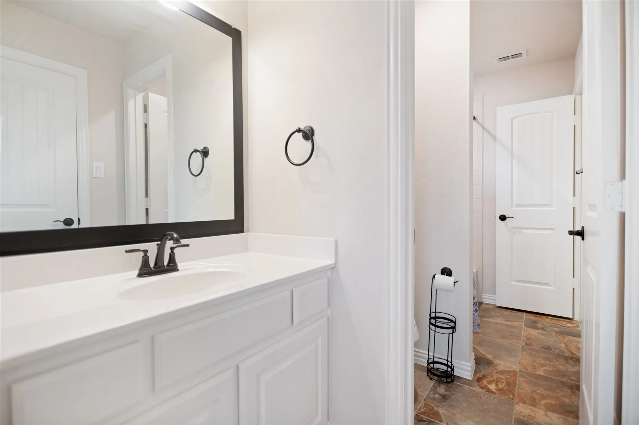 Bathroom vanity featuring a white countertop, an undermount sink, and a dark bronze two-handle faucet