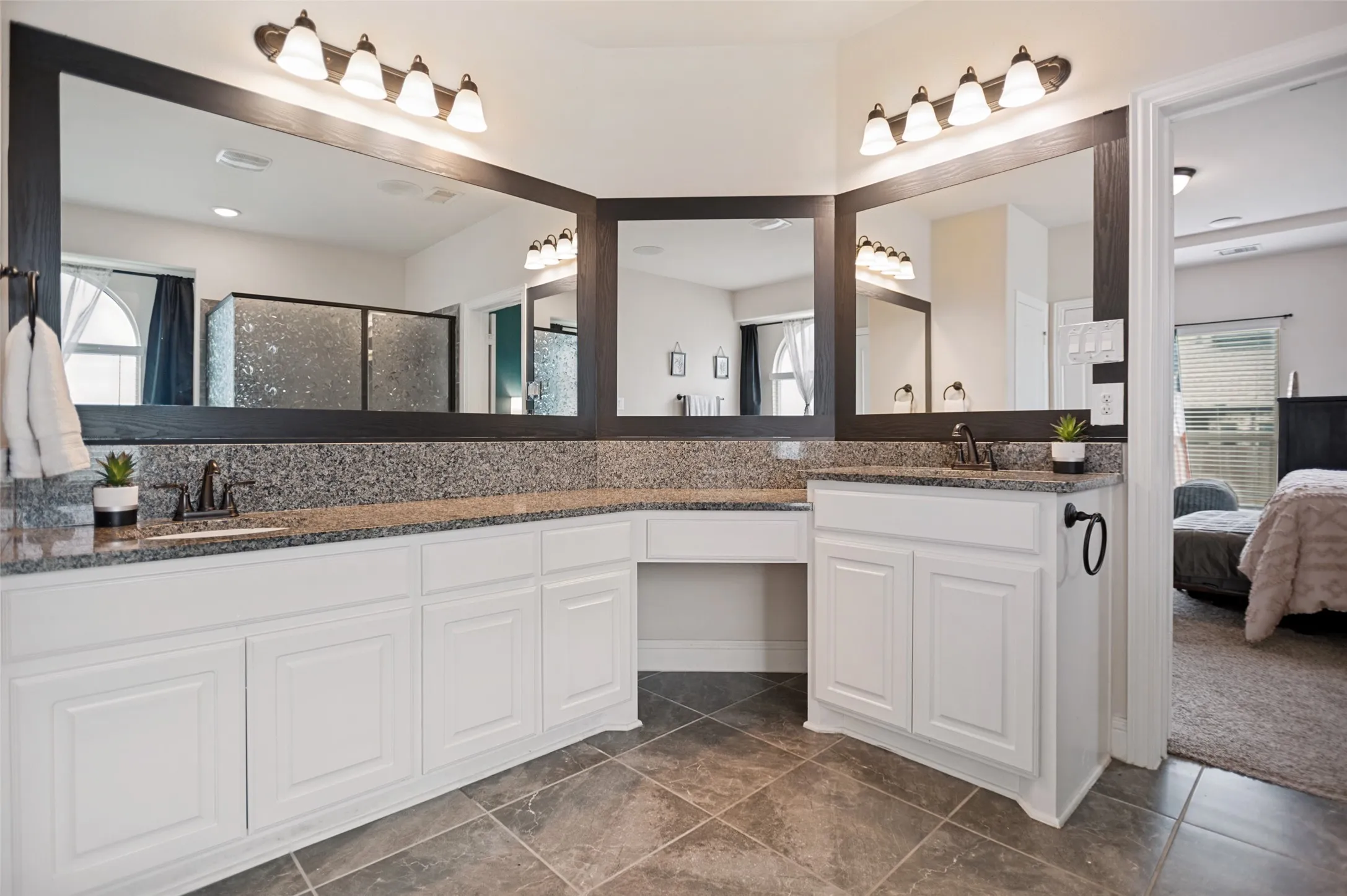 Dual vanity with integrated sinks and dark bronze fixtures, framed mirrors, and granite countertops