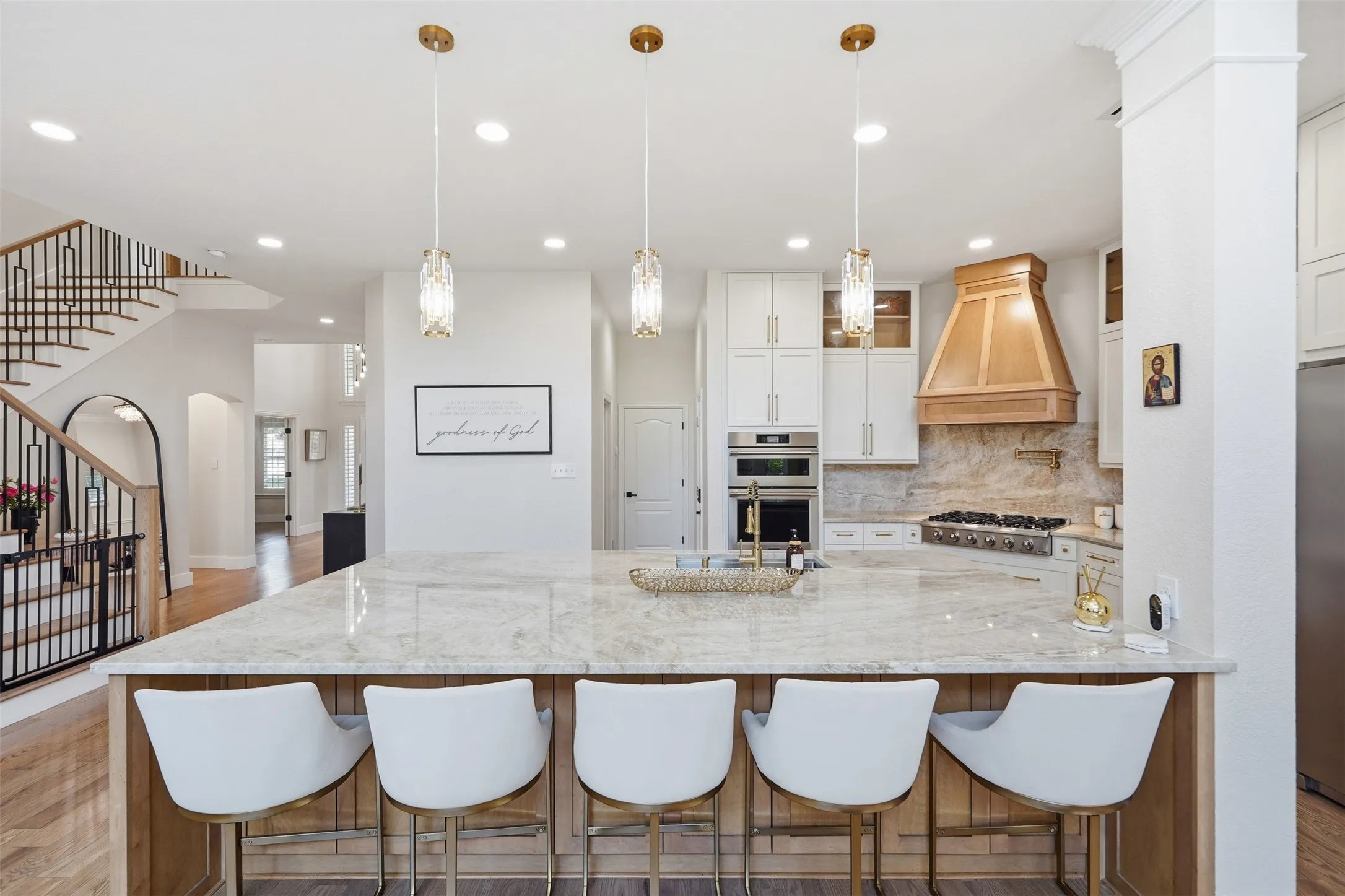 Expansive kitchen island with a light-toned countertop, wood-finish base, and three pendant lights