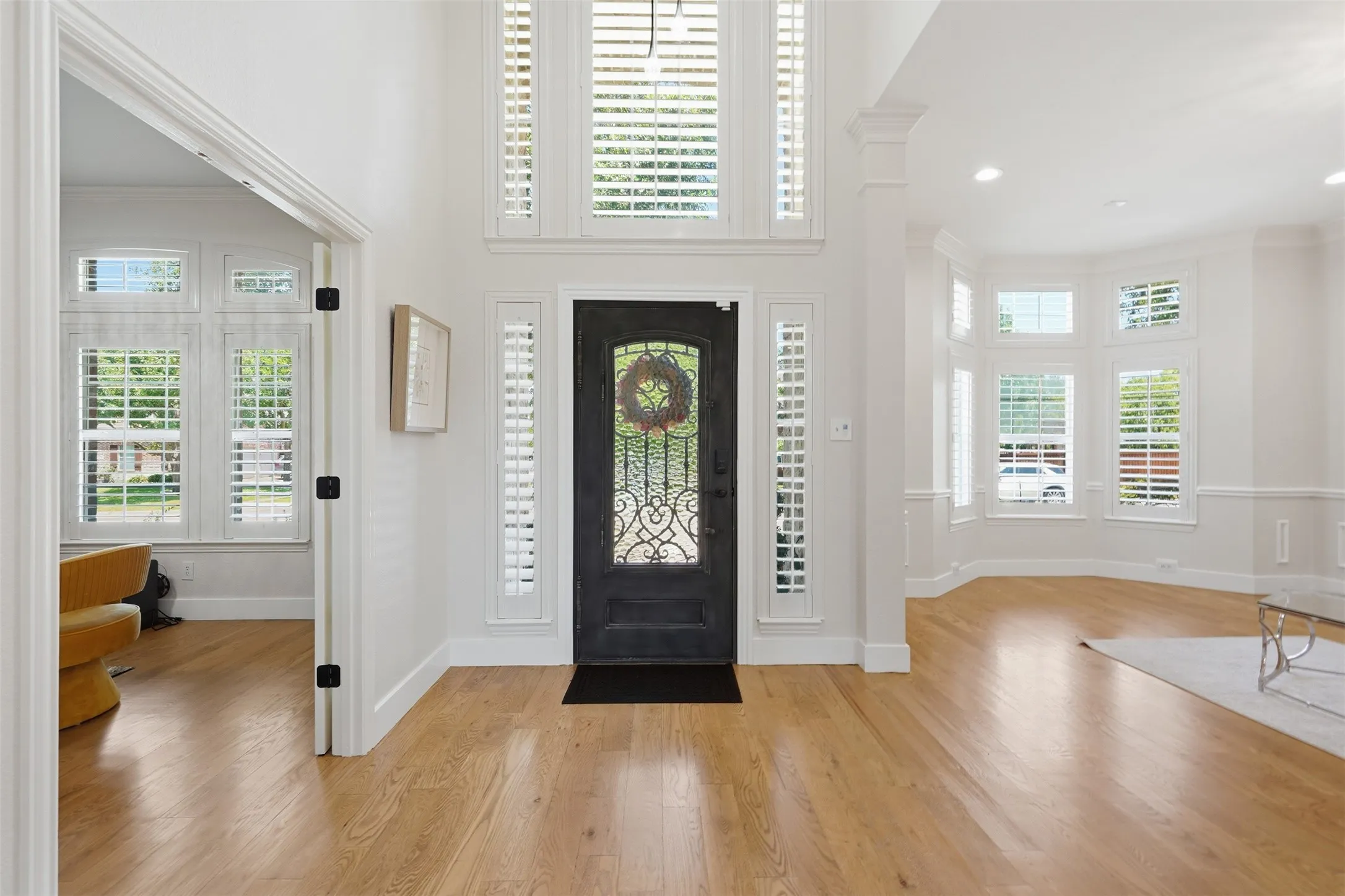 Entry with a dark-finish door featuring decorative ironwork, flanked by sidelights and transoms with louvered shutters