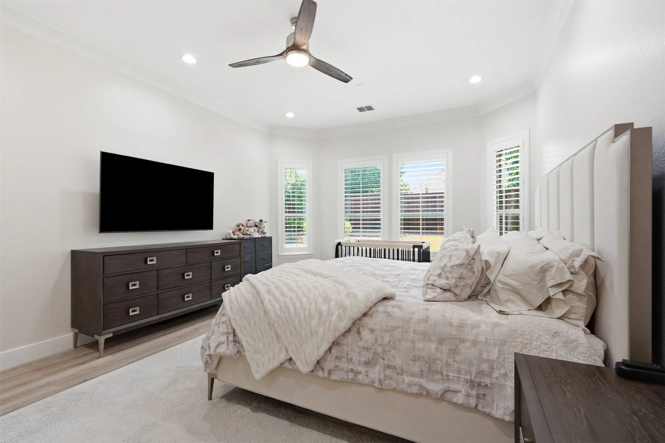 Recessed lighting, crown molding, wood-finish flooring, bay window with plantation shutters, and a ceiling fan with integrated lighting