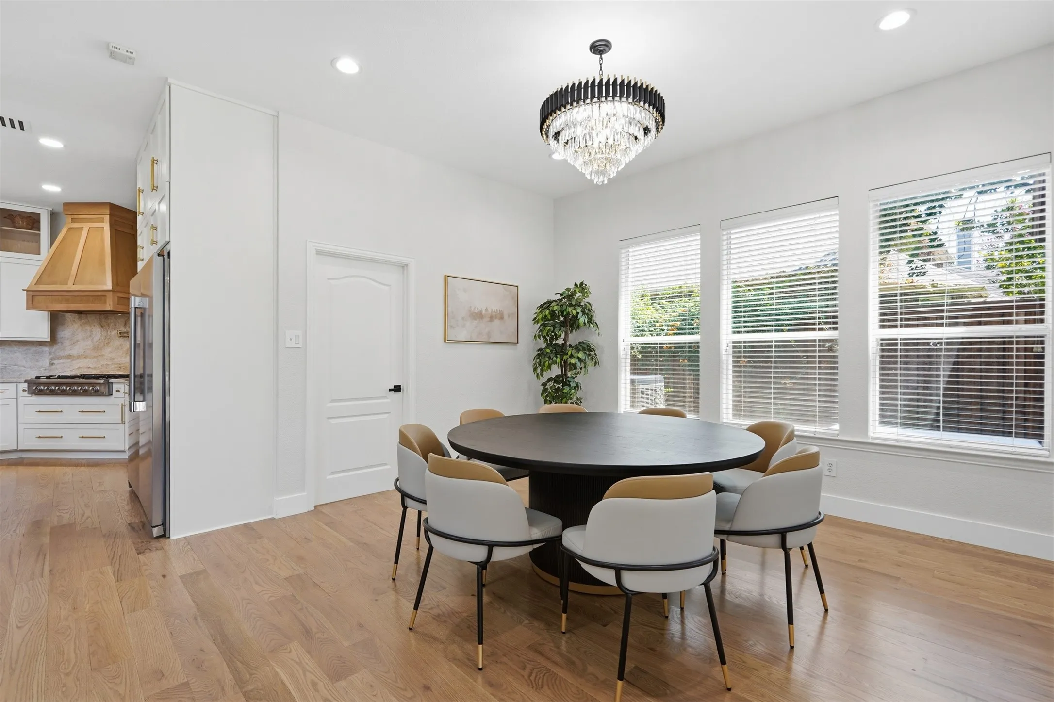 Hardwood flooring extends throughout the space, complemented by a tiered chandelier and recessed lighting