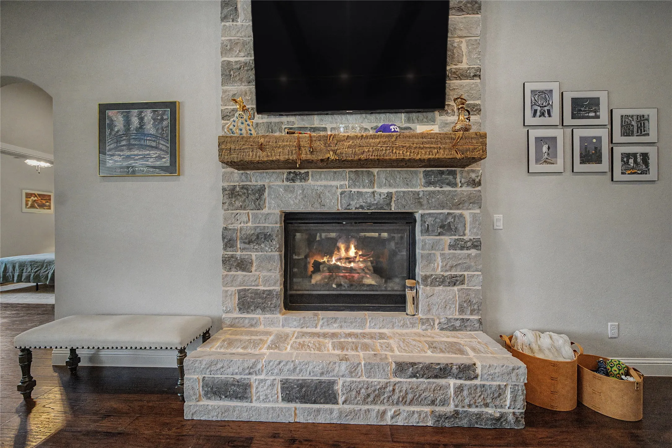 Stone-clad fireplace featuring a hearth, dark wood-finish flooring, and a substantial wood mantel