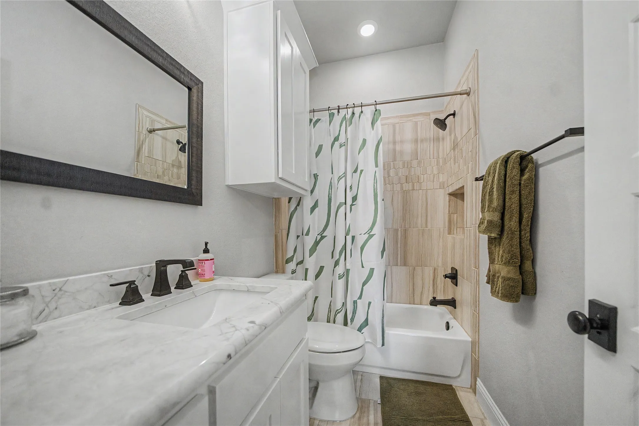 Full bathroom featuring a single vanity with stone countertop, undermount sink, and dark bronze fixtures