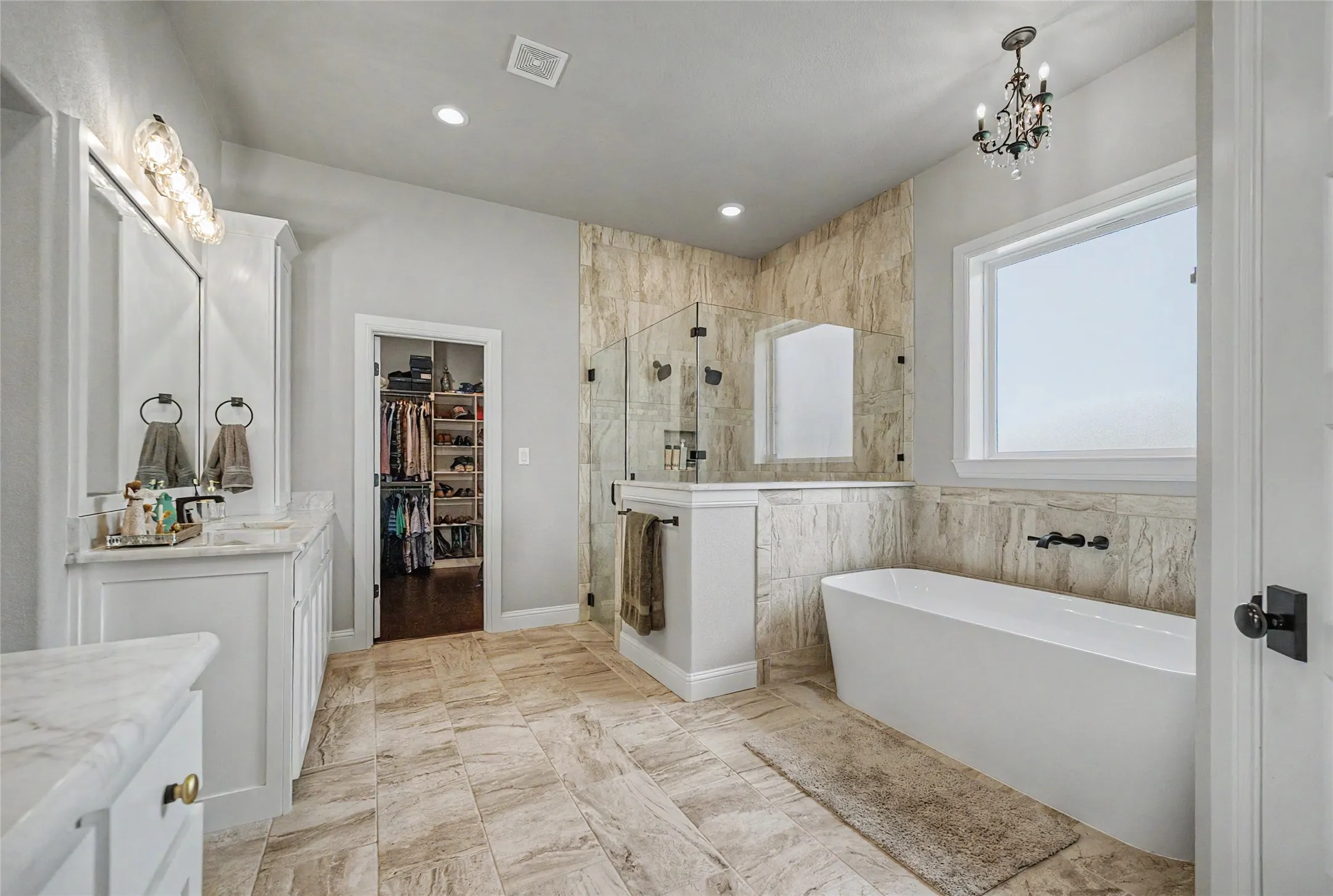 Spacious bathroom featuring a freestanding tub, glass-enclosed shower, and dual vanity with stone countertops
