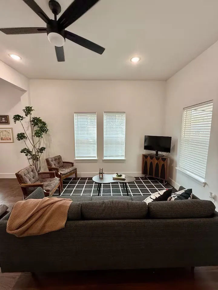 Living area featuring wood-finish flooring, two large windows with blinds, recessed lighting, and a ceiling fan