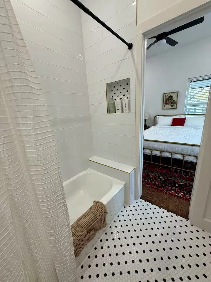 Bathroom featuring a white subway tile surround, built-in shower niche, and a white bathtub