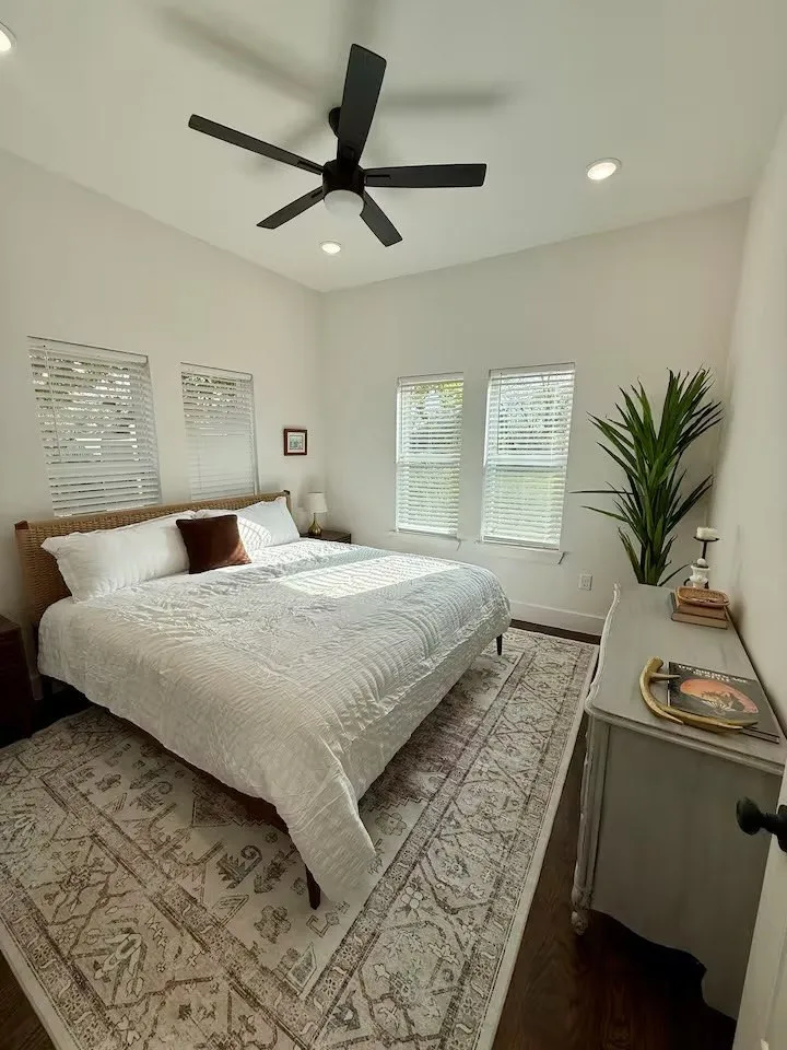Spacious room featuring vaulted ceilings, a contemporary ceiling fan with integrated lighting, recessed lighting, wood-finish flooring, and multiple windows