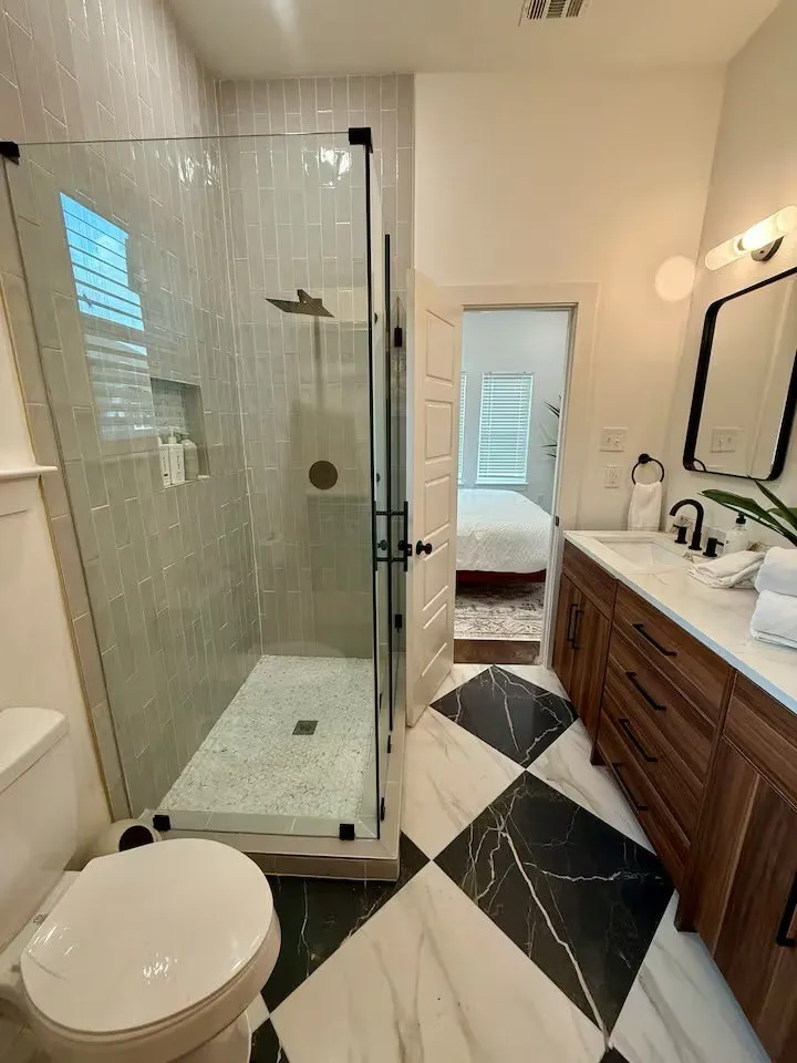 Spacious bathroom featuring a glass-enclosed shower with subway tile surround, rainfall showerhead, and built-in niche