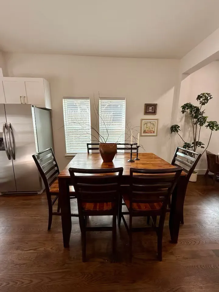 Kitchen dining area featuring wood-finish flooring, white cabinetry with stainless steel hardware, and a stainless steel refrigerator