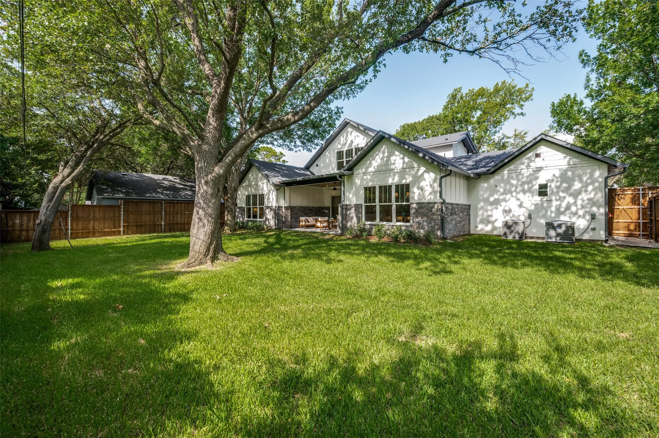Spacious backyard featuring a lush lawn, established trees, and a wood privacy fence