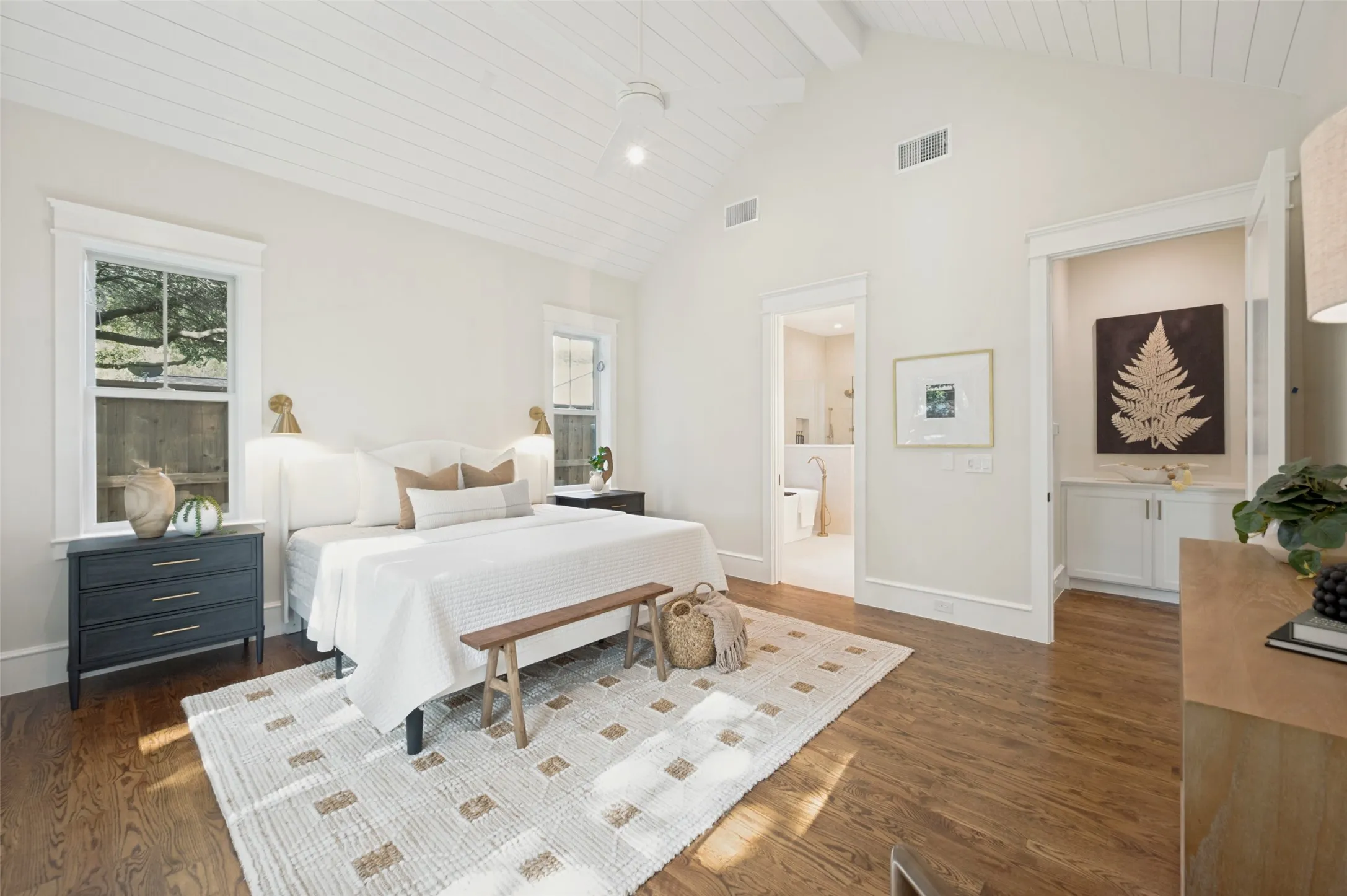Spacious room featuring vaulted ceilings with shiplap finish, wood-finish flooring, and multiple windows with exterior views
