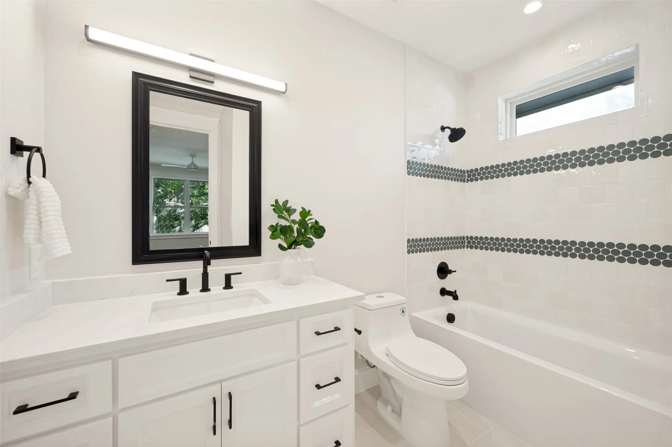 Contemporary bathroom featuring a white vanity with integrated sink, quartz countertop, and matte black fixtures