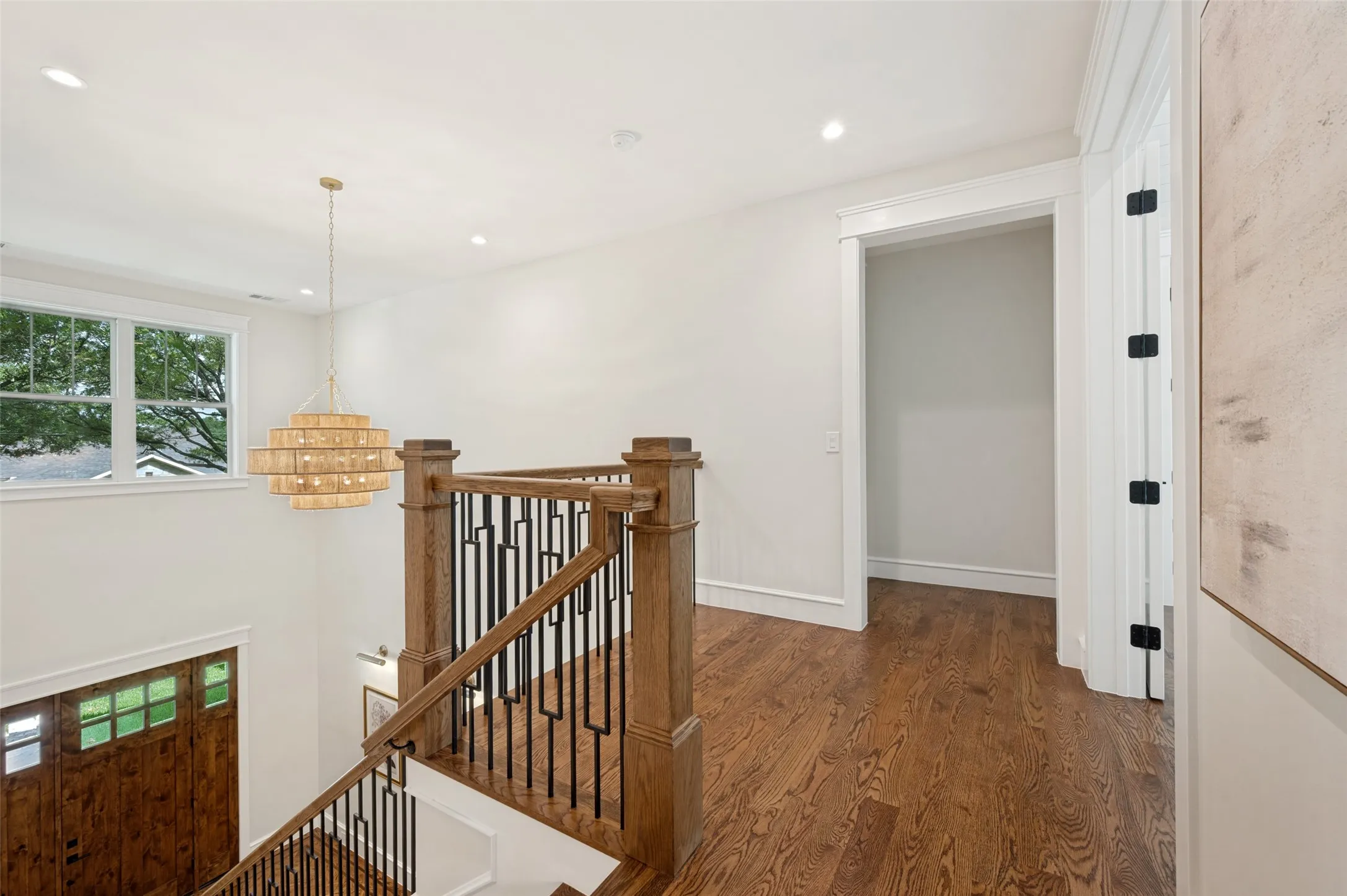 Hardwood flooring throughout the upper landing, featuring a contemporary chandelier and recessed lighting