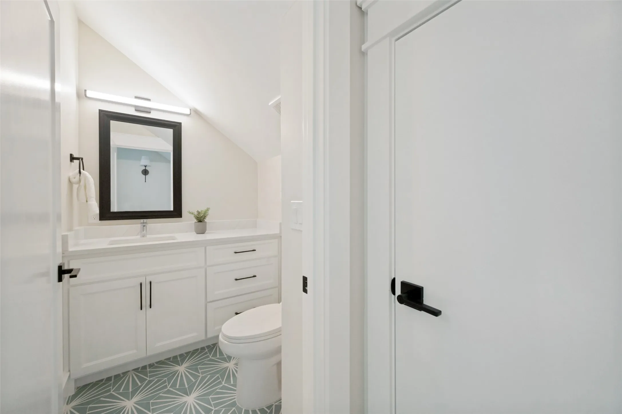 Bathroom featuring a white vanity with integrated sink, a rectangular mirror, and a geometric pattern floor tile