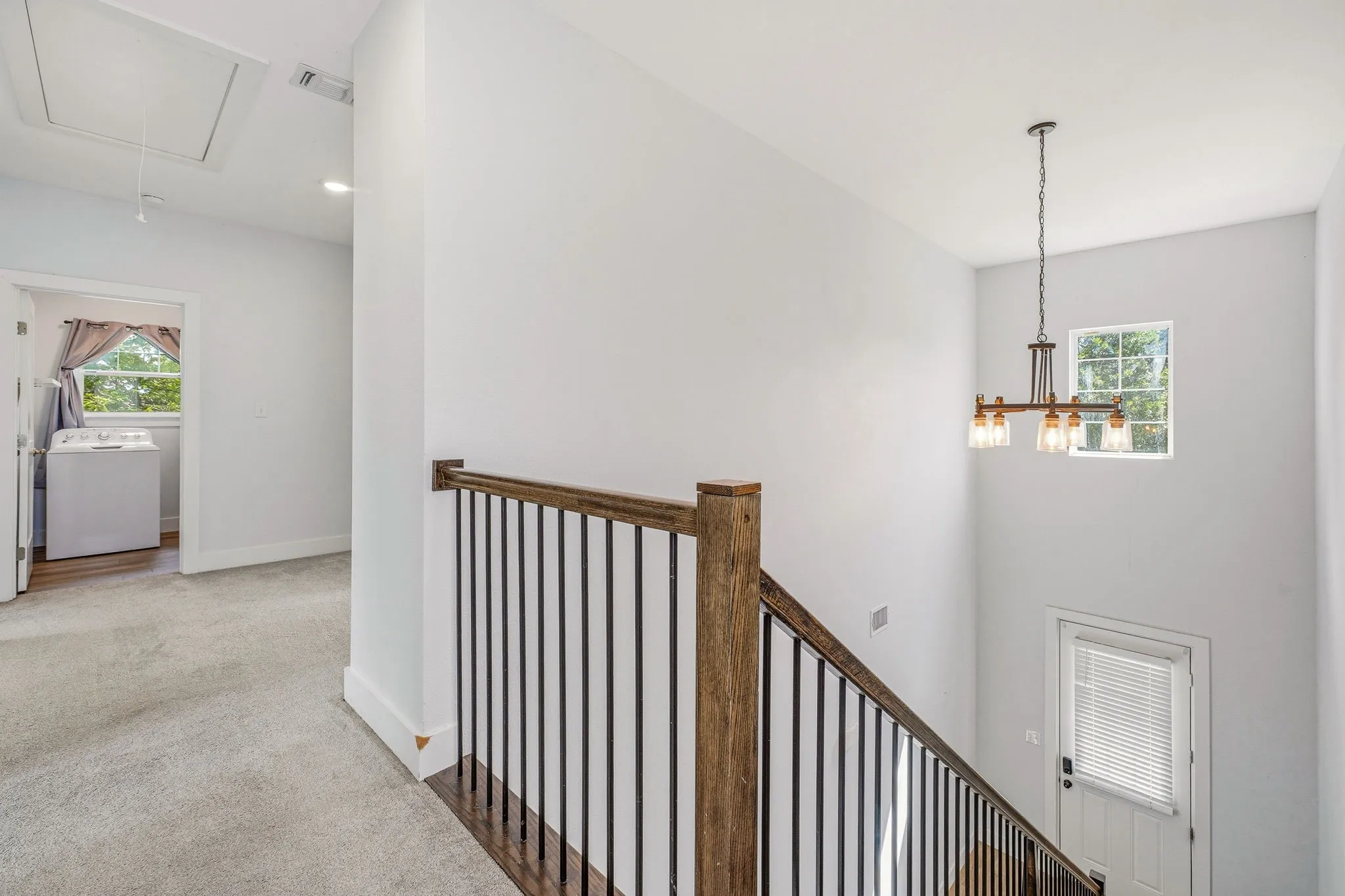 Upper-level hallway featuring a wood-finish staircase railing with black metal spindles