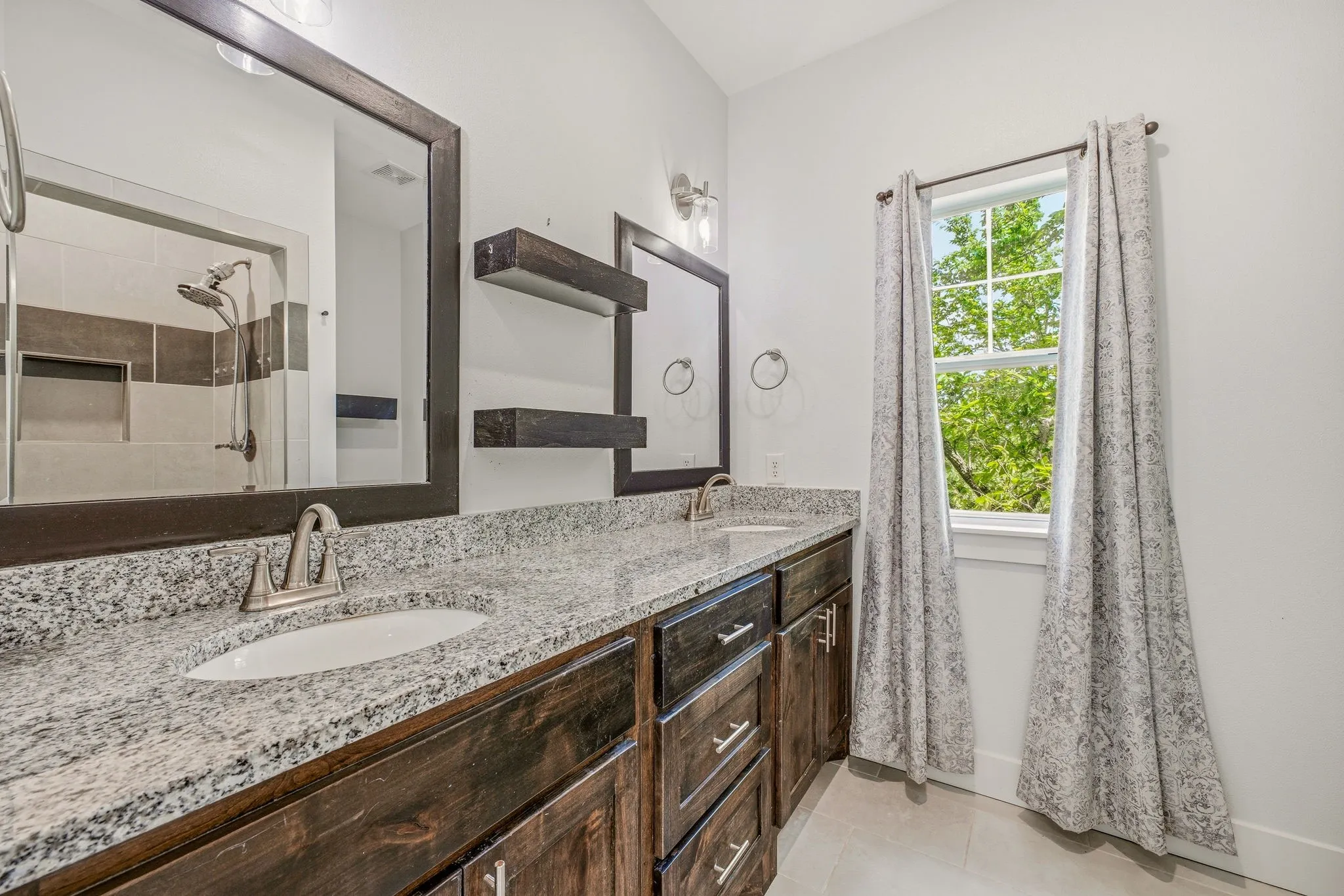Dual vanity with granite countertop, dark wood-finish cabinetry, and brushed nickel fixtures