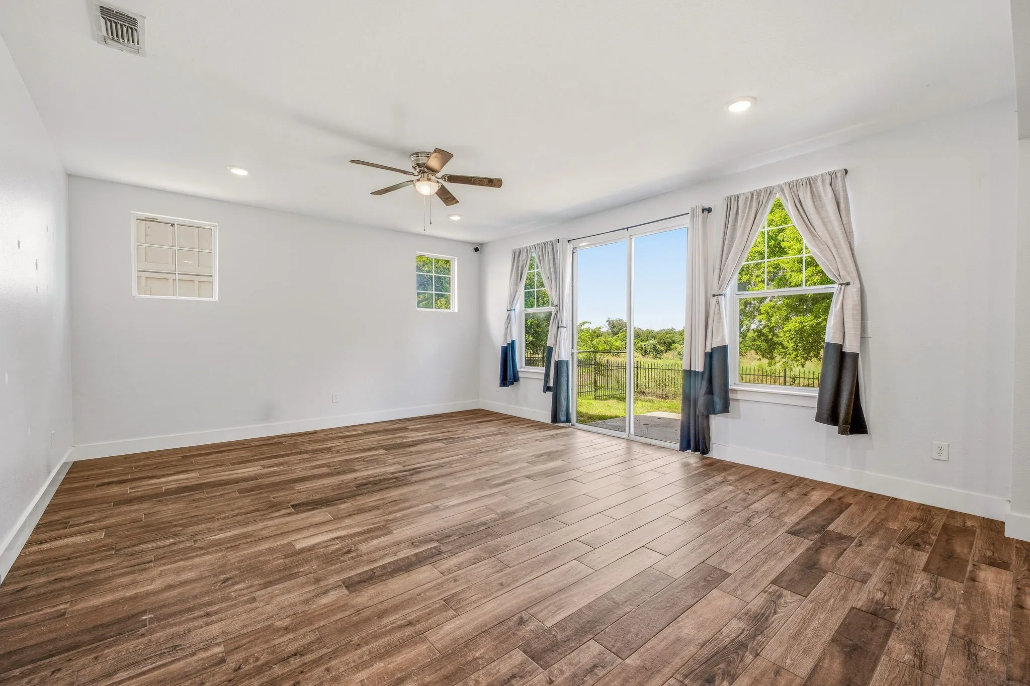 Spacious room featuring wood-finish flooring, recessed lighting, and a ceiling fan