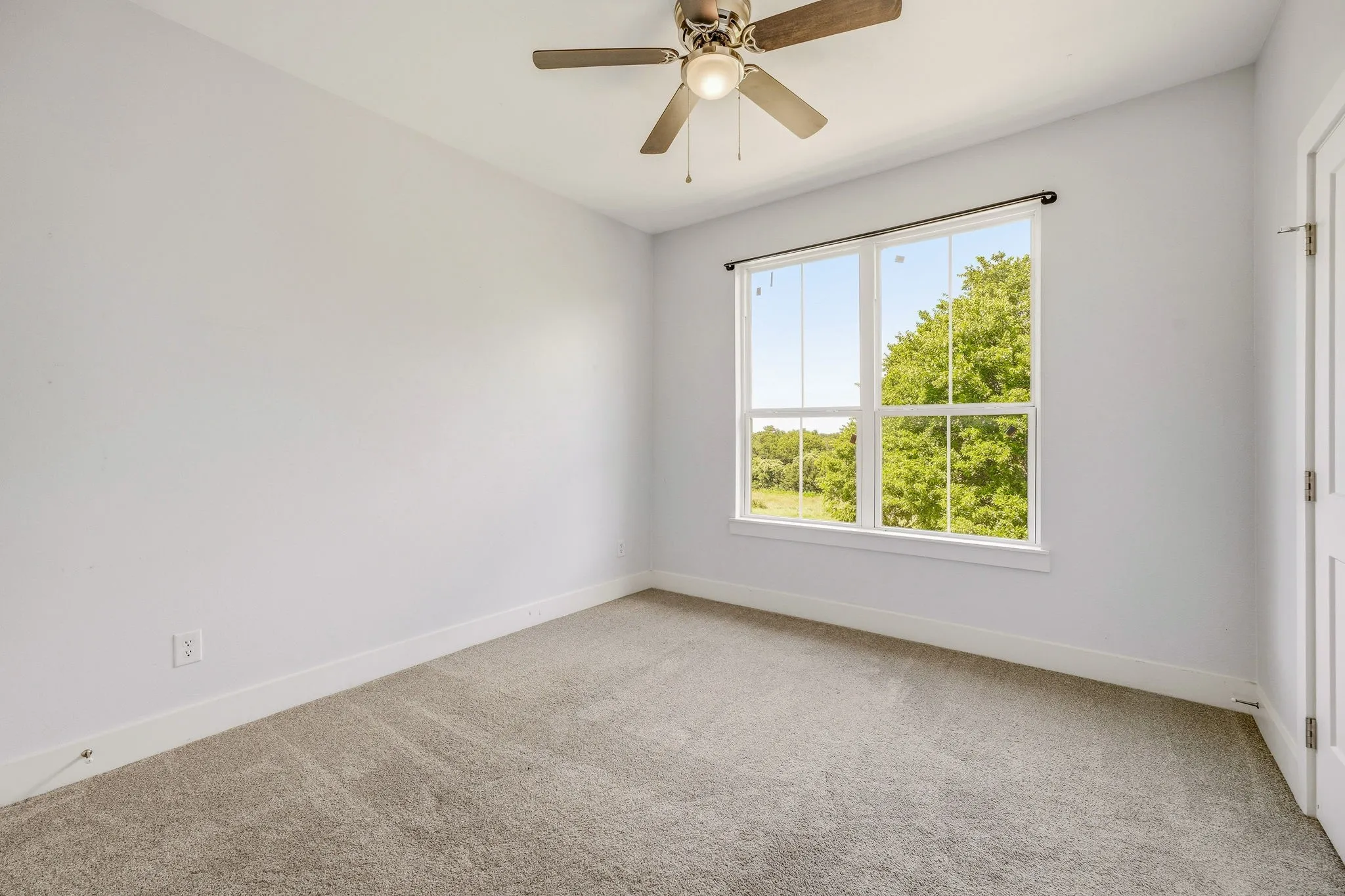 Bright room featuring a large window with white trim, a multi-pane design, and an overhead ceiling fan with integrated lighting
