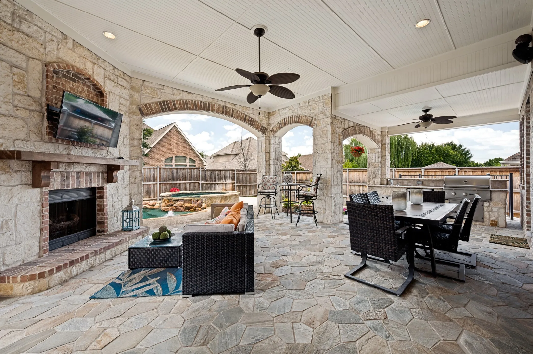 A covered patio provides year round enjoyment  with shade in the summer  and a cozy fireplace in the winter.