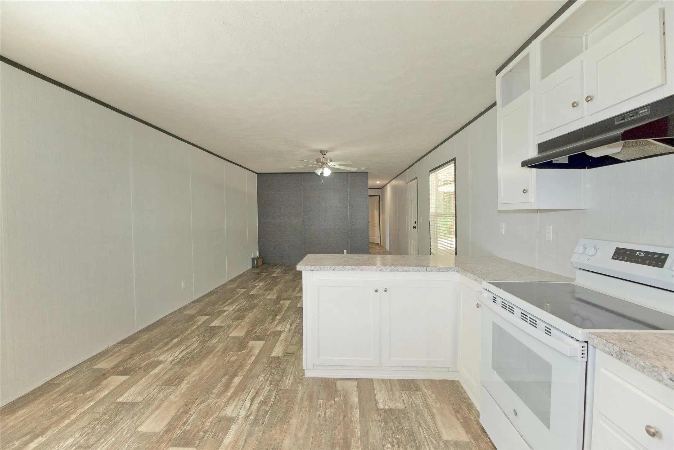 Kitchen featuring white cabinetry, light-toned countertops, and a white electric range