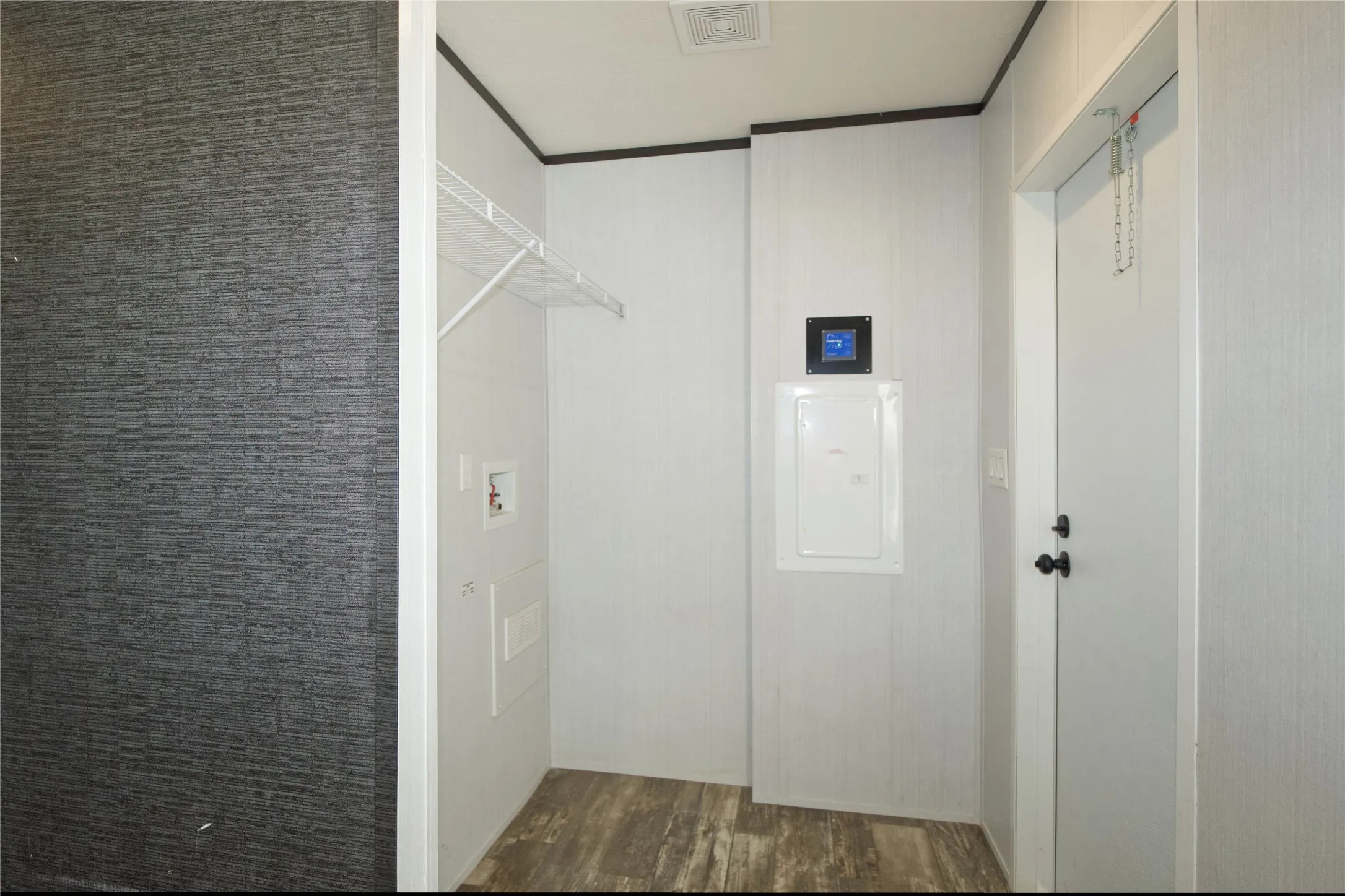 Dedicated utility area featuring wood-finish flooring and a white wire shelf